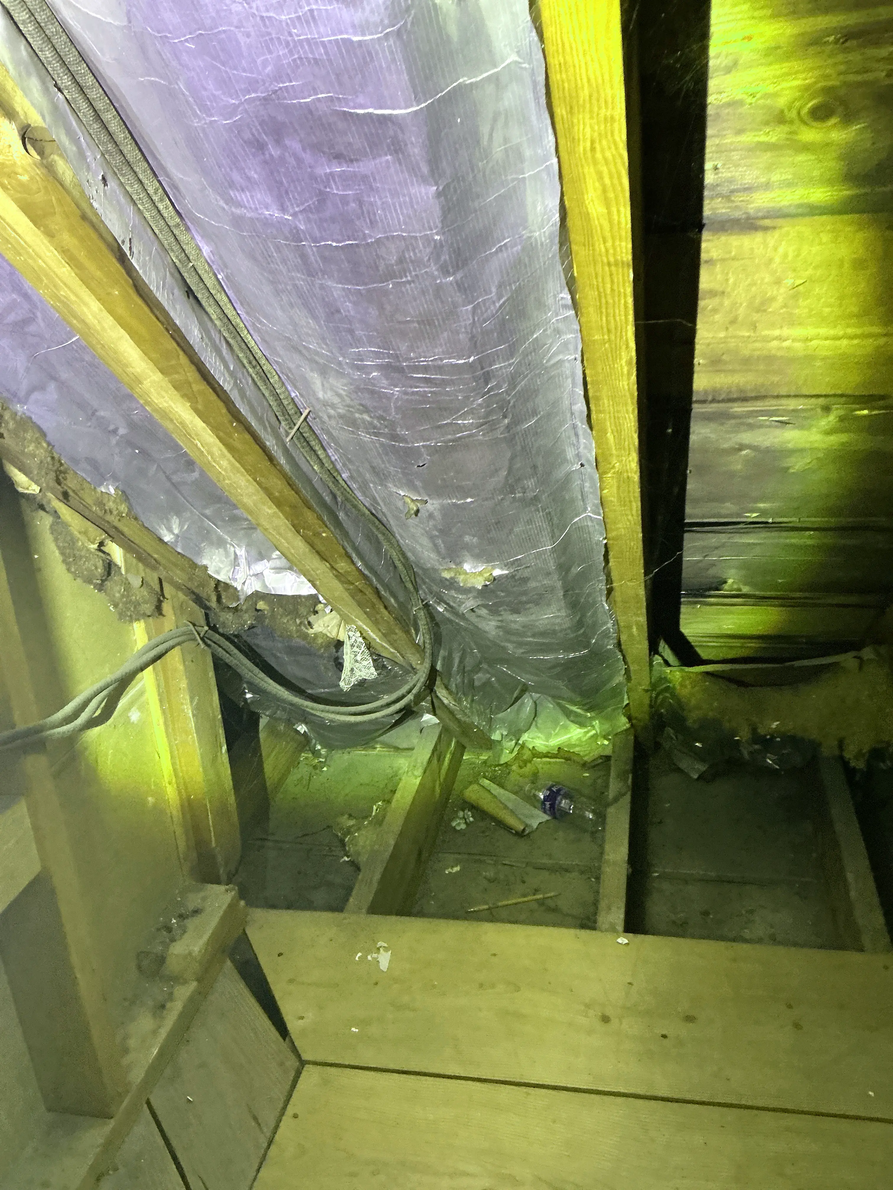 Insulated flexible HVAC duct and electrical cables running along wooden joists in an attic space 2026-07-17