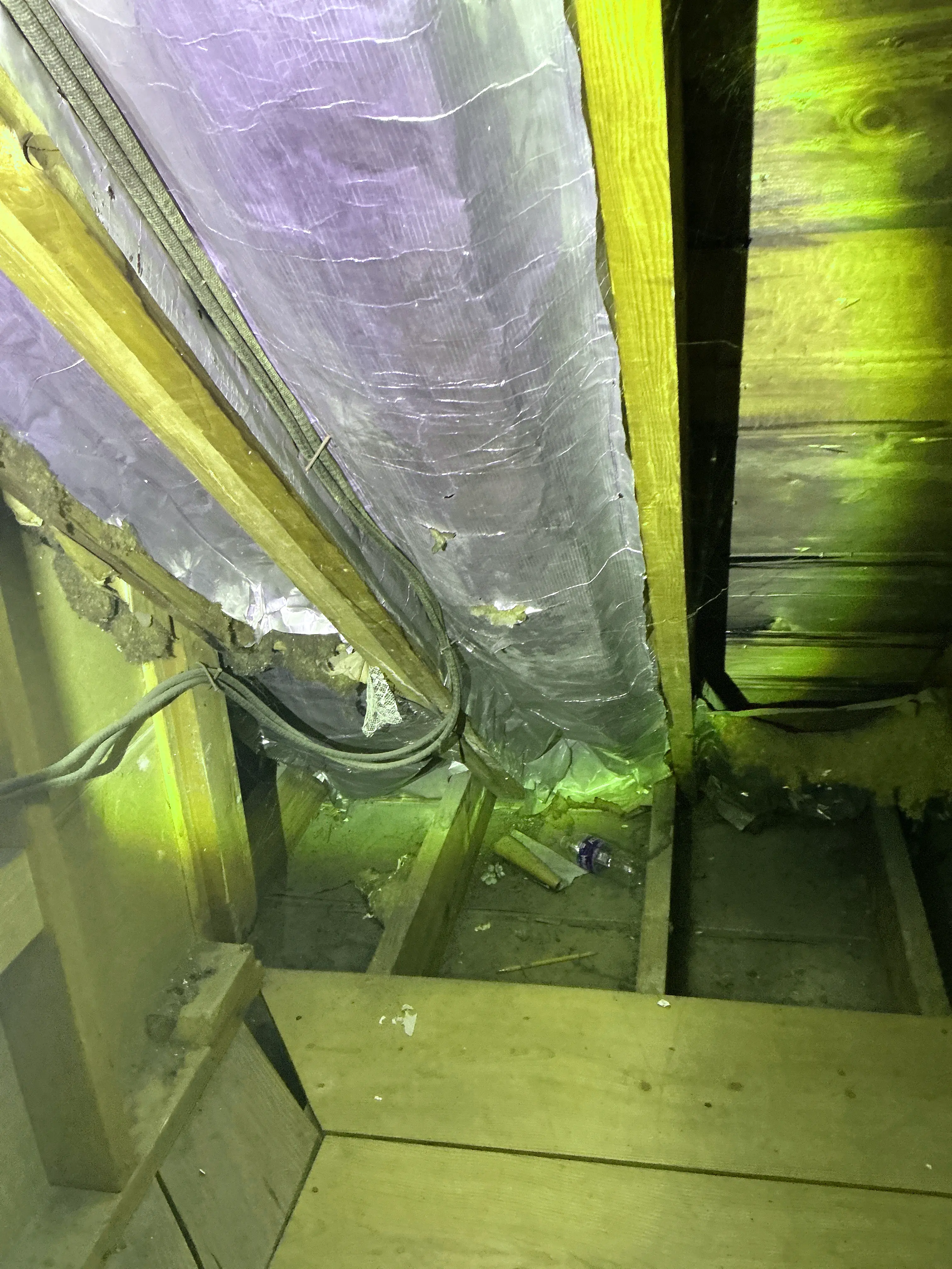 Insulated flexible HVAC duct and electrical cables running along wooden joists in an attic space 2026-08-29