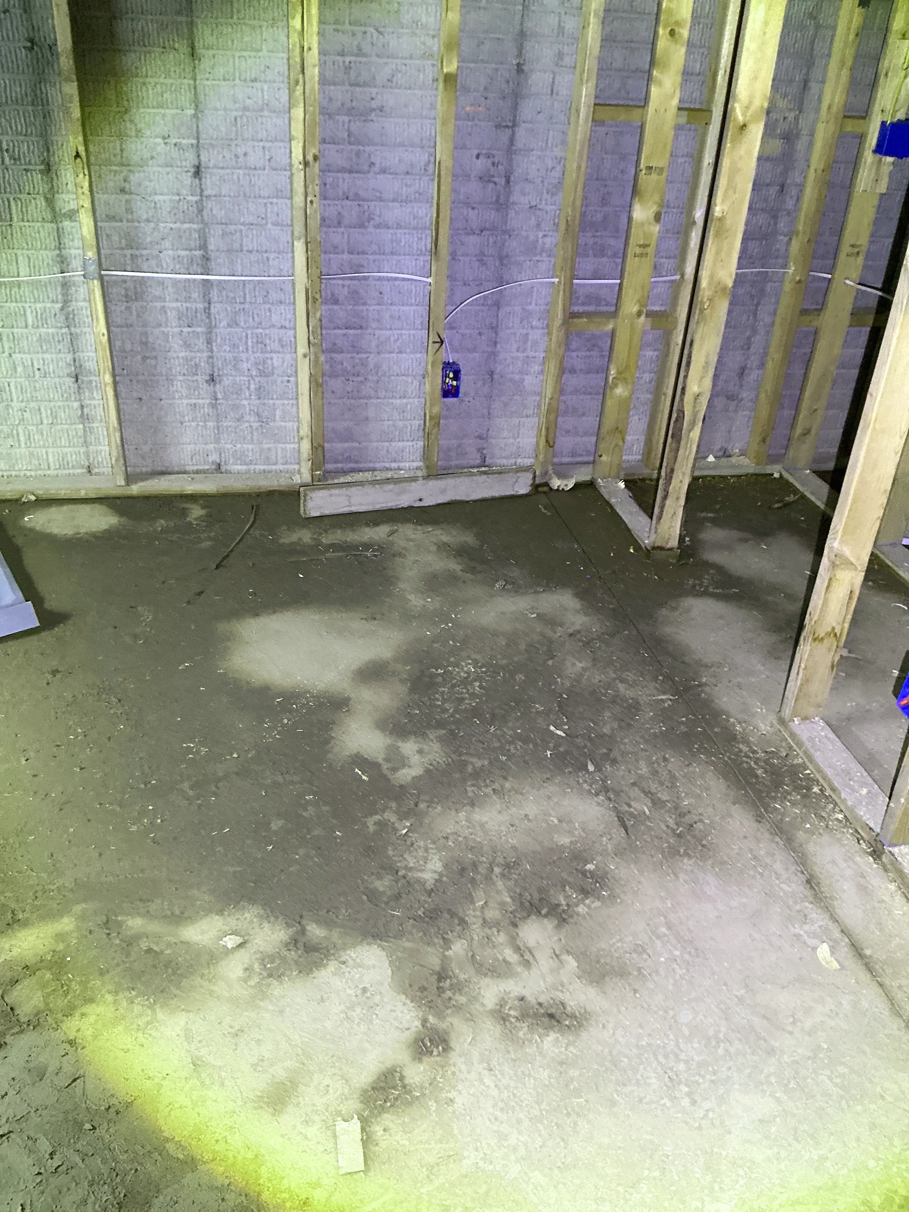Moisture and water staining on a concrete floor near framed walls in an unfinished basement 2026-08-19