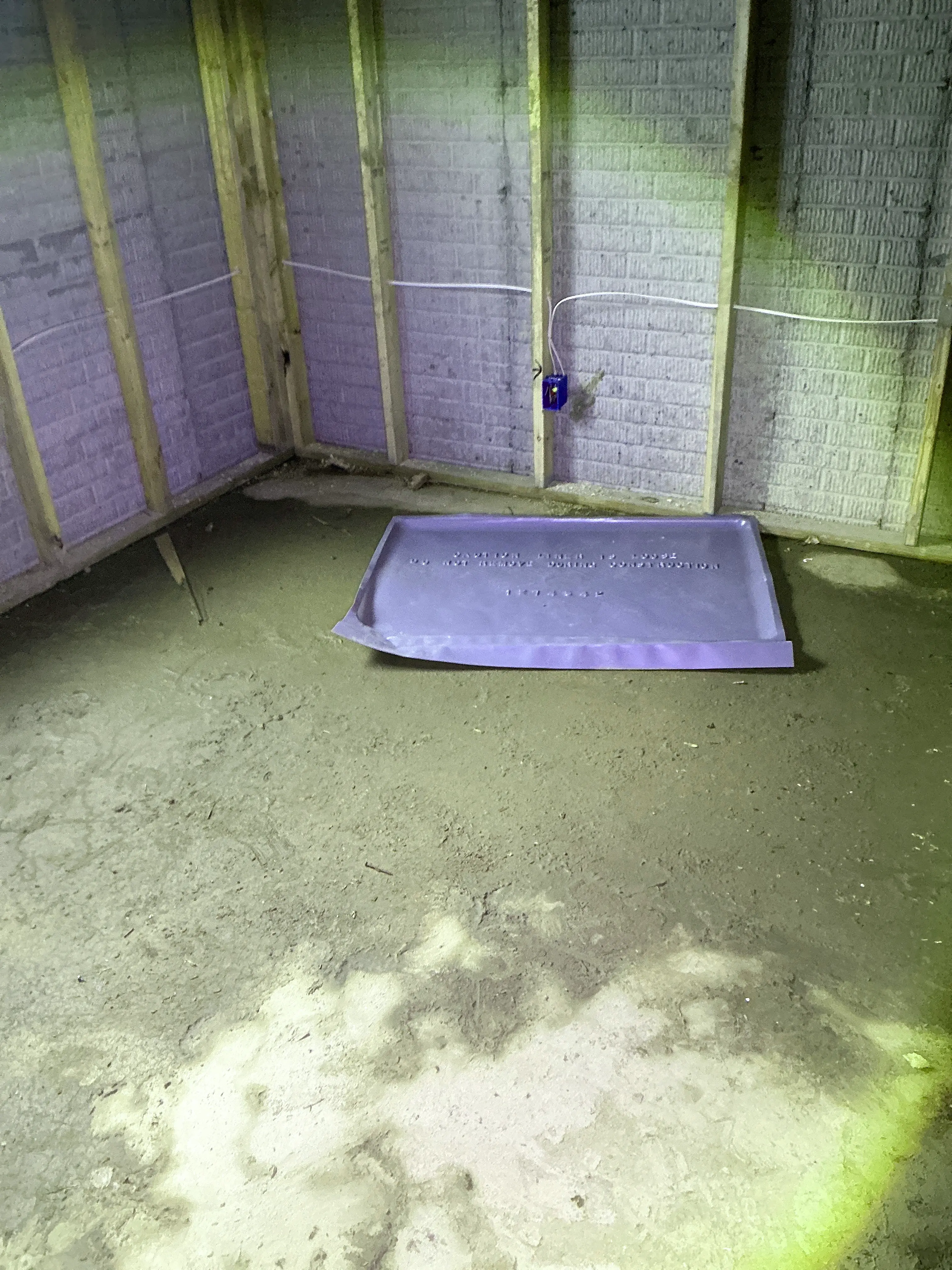 Unfinished basement dirt floor with exposed wall framing, electrical junction box, and plastic pan. 2026-07-09