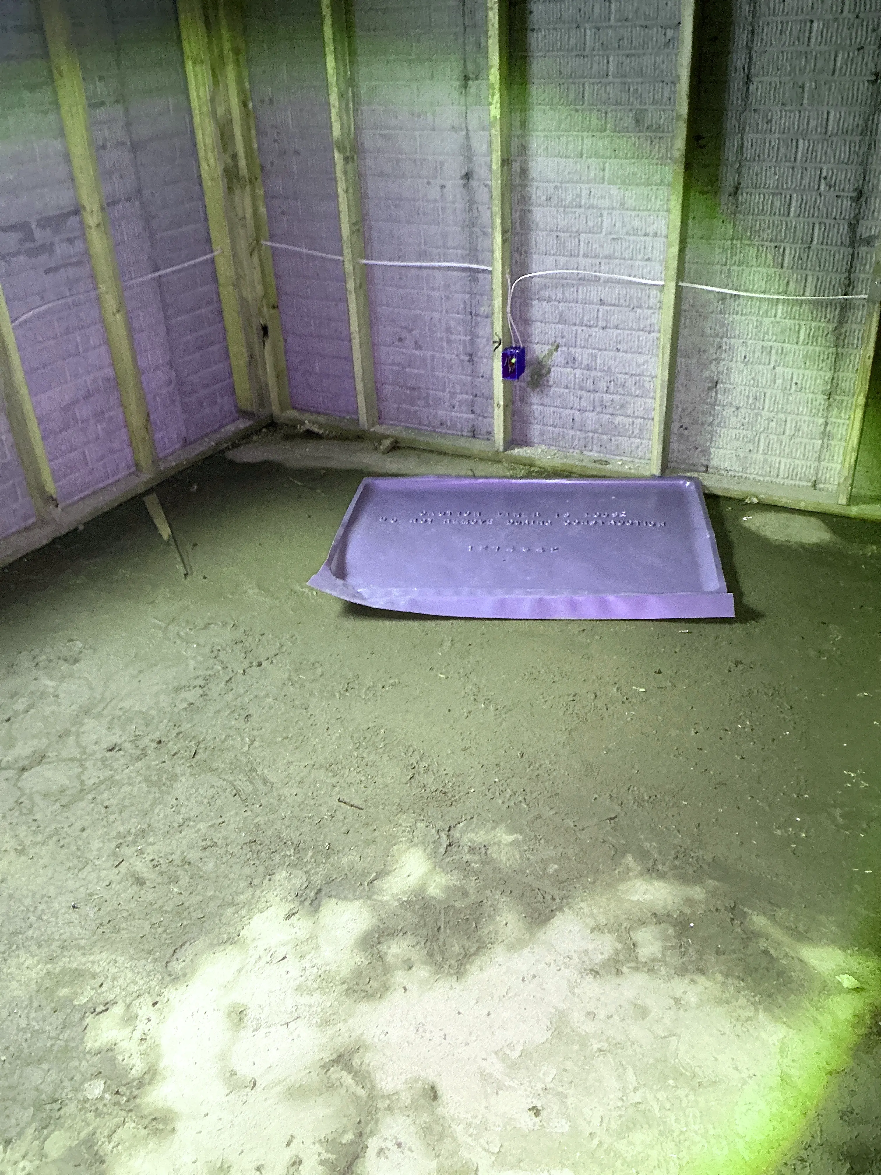 Unfinished basement dirt floor with exposed wall framing, electrical junction box, and plastic pan. 2026-08-07