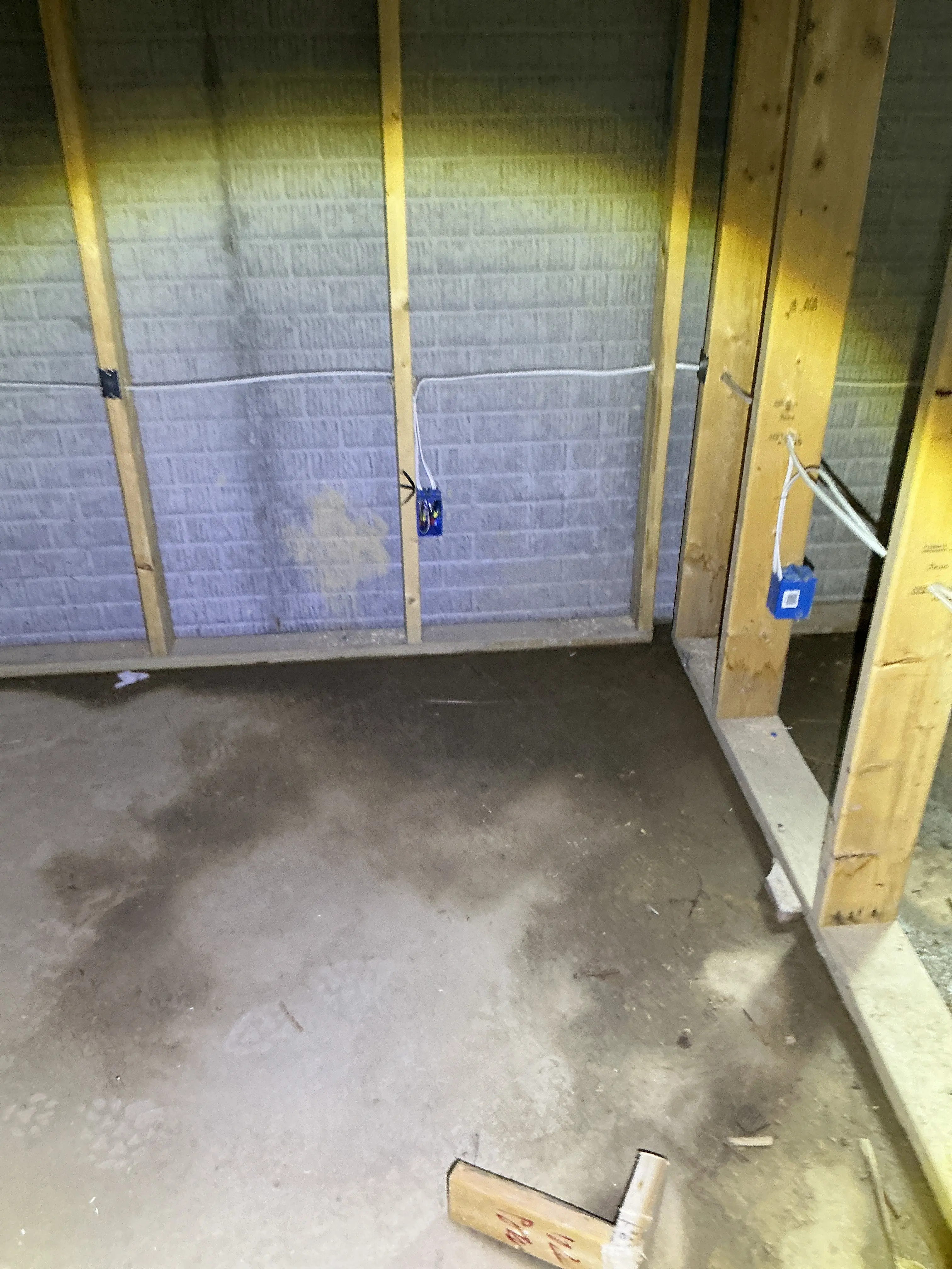 Rough-in electrical wiring and blue outlet boxes installed on wooden wall studs in an unfinished basement 2026-07-19