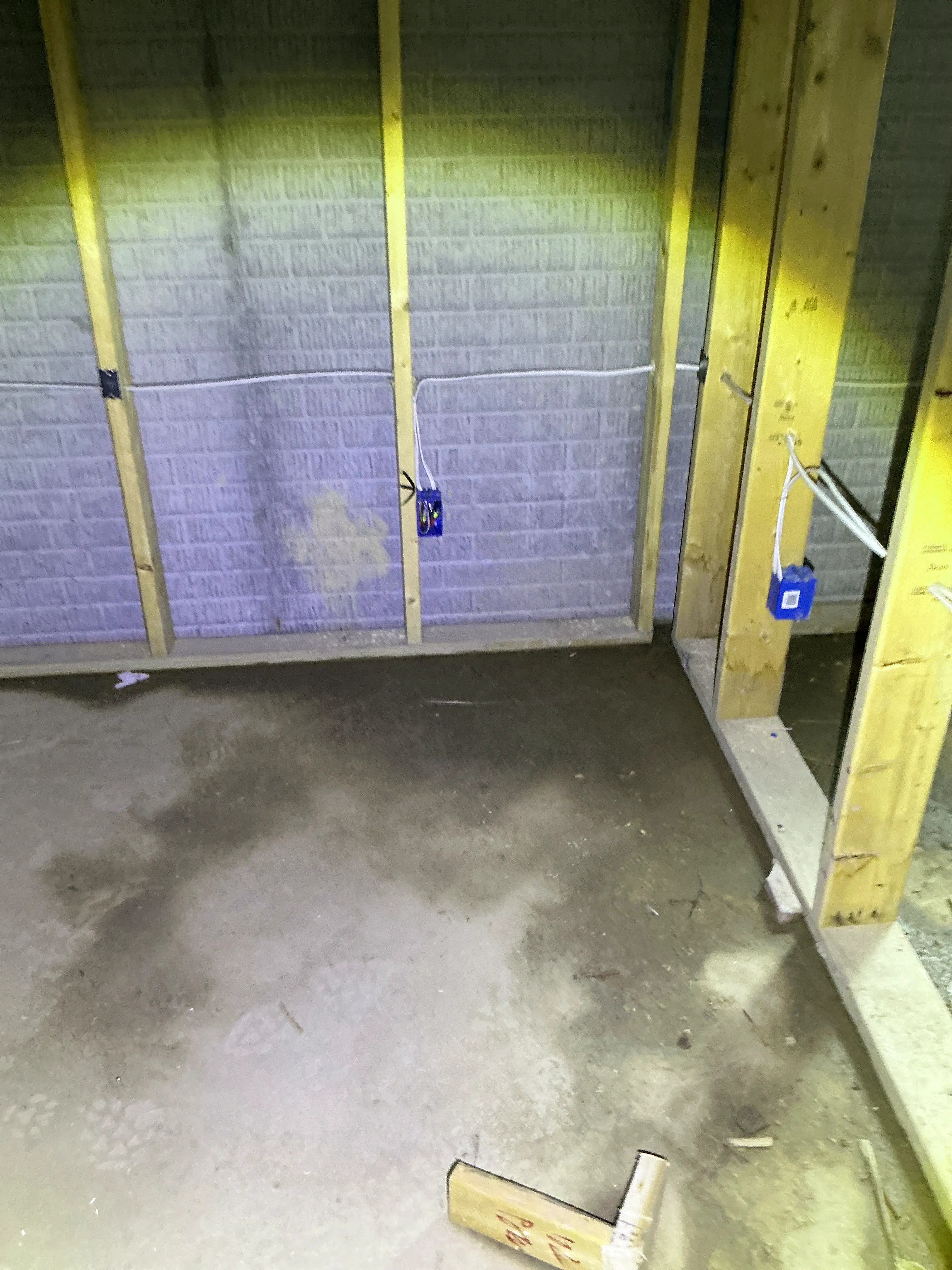 Rough-in electrical wiring and blue outlet boxes installed on wooden wall studs in an unfinished basement 2026-07-04