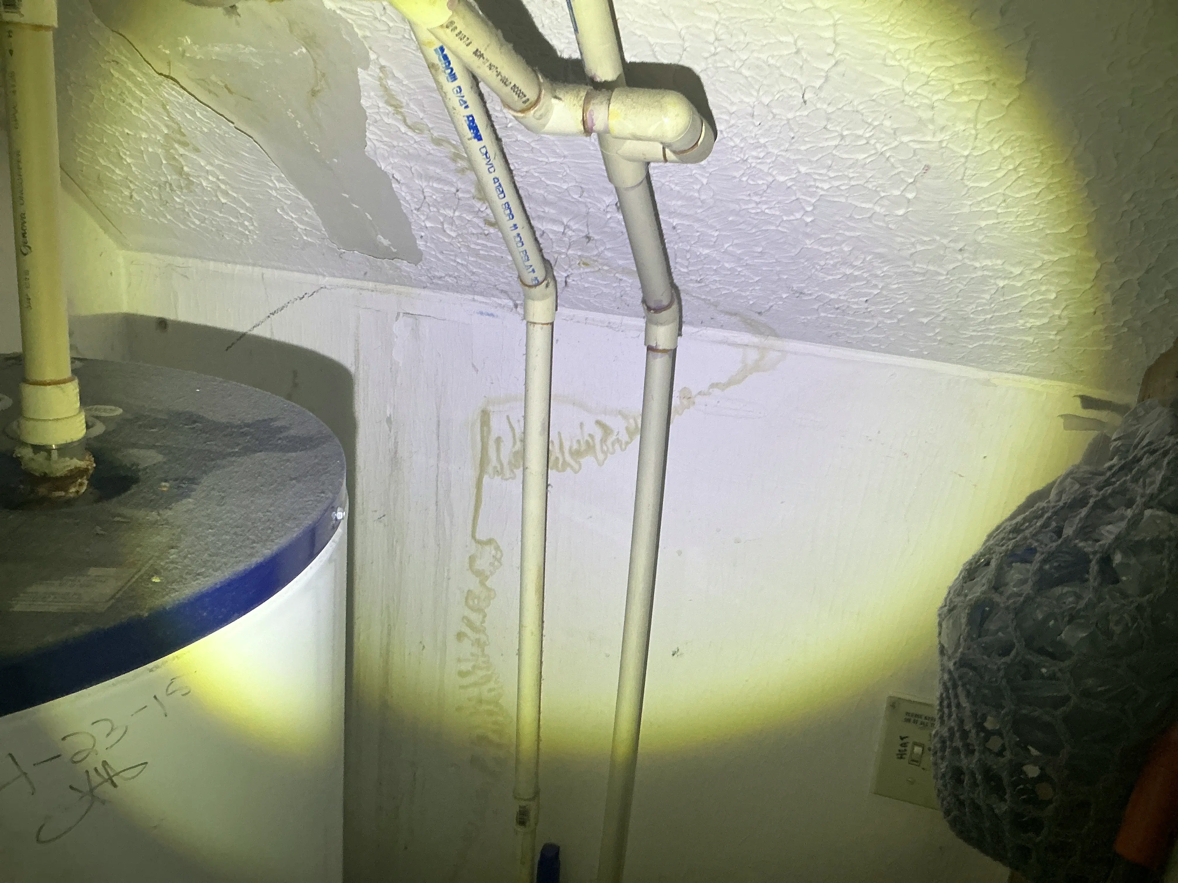Water staining on drywall behind CPVC plumbing pipes next to a water heater 2026-08-17