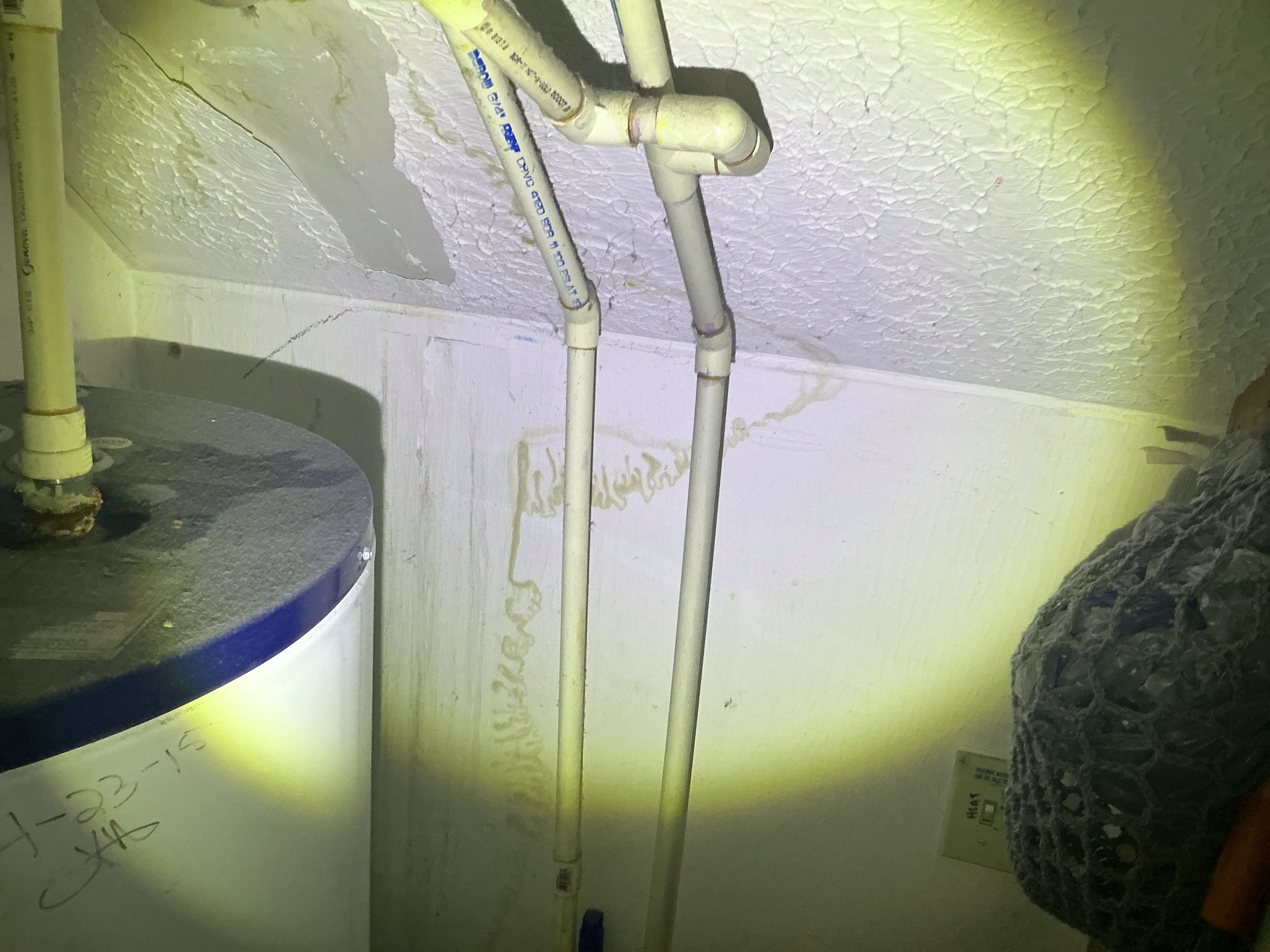 Water staining on drywall behind CPVC plumbing pipes next to a water heater 2026-08-07