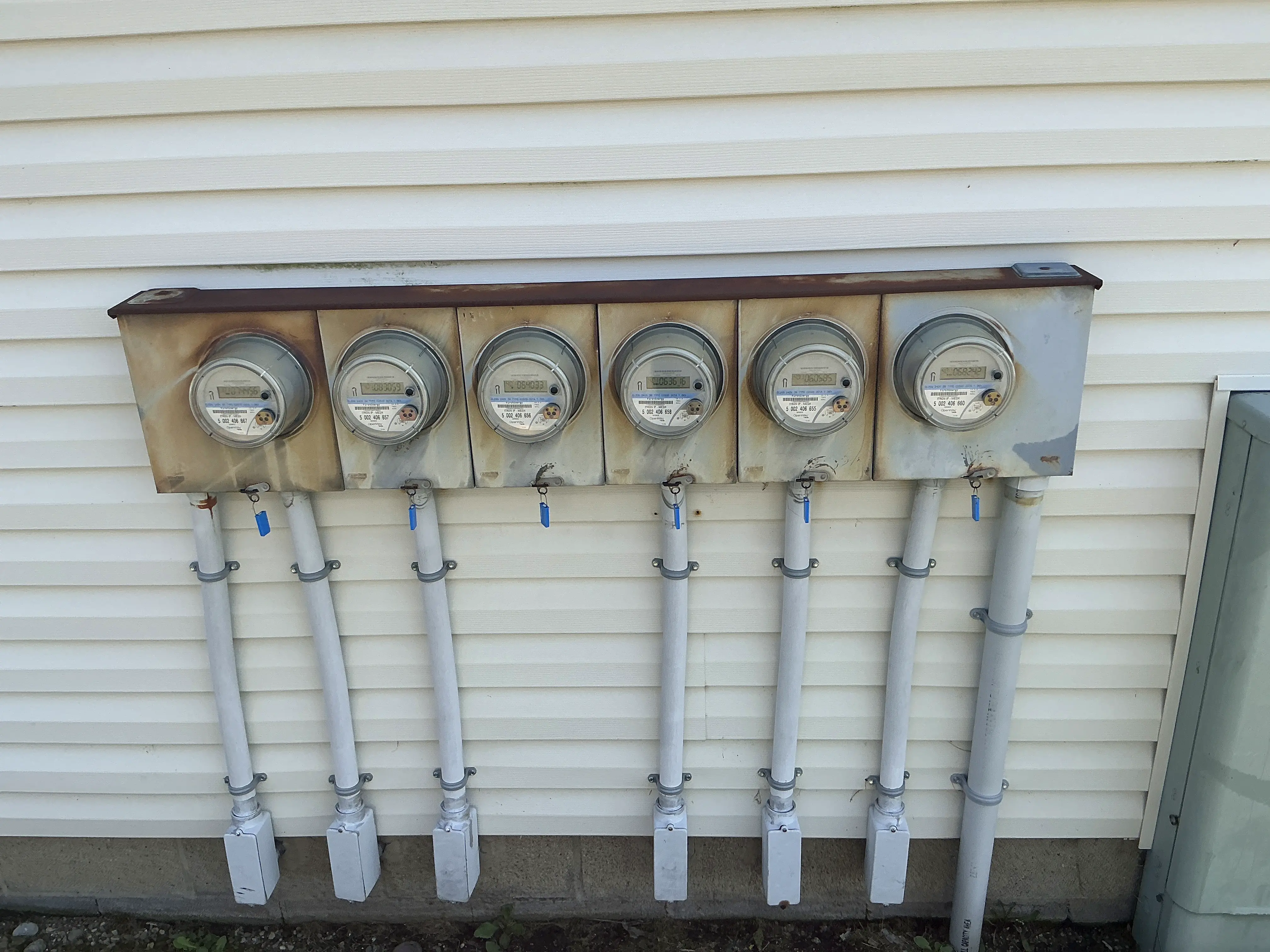 Bank of electric meters installed on exterior siding of multi-unit building 2026-07-21