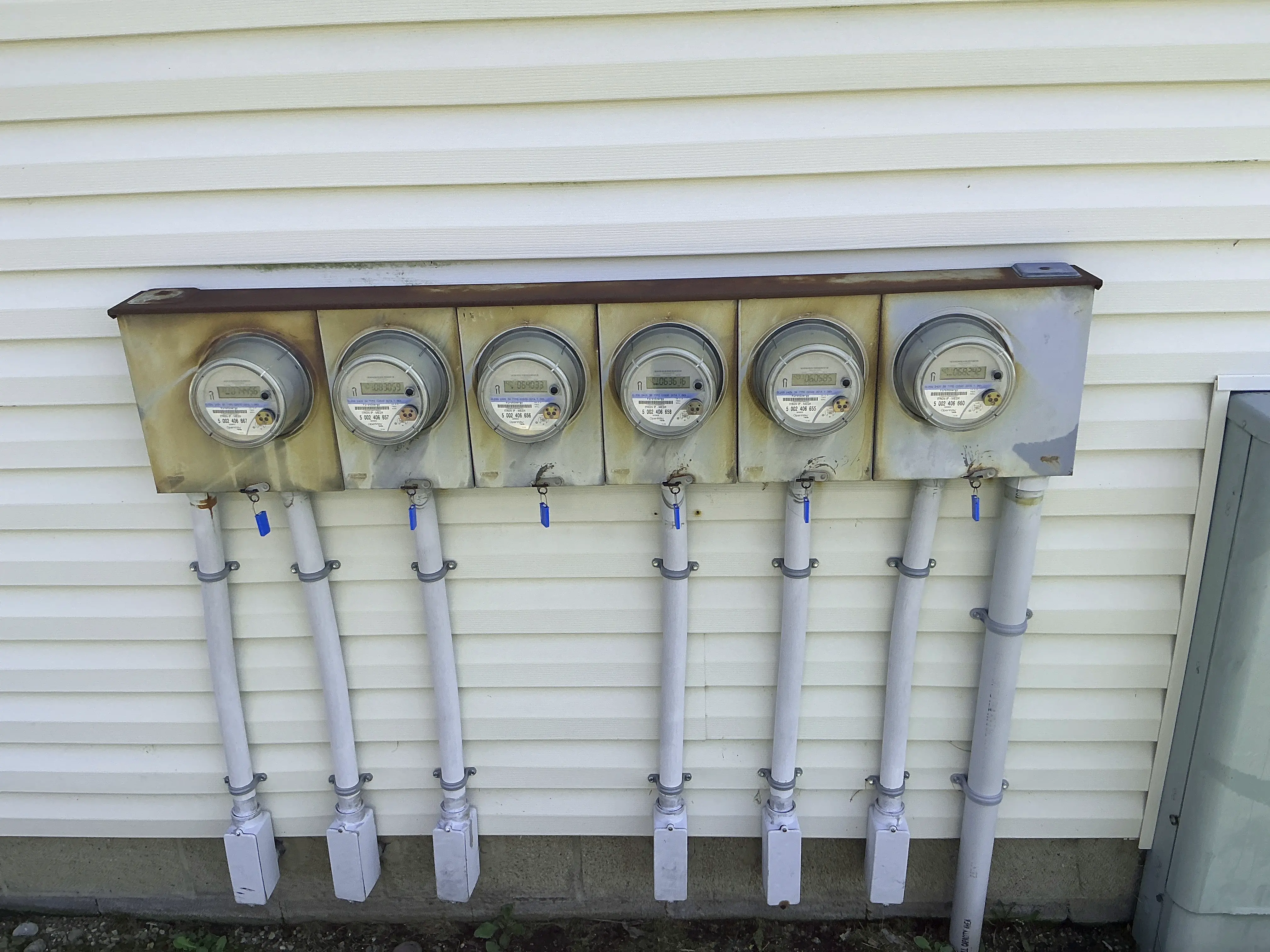 Bank of electric meters installed on exterior siding of multi-unit building 2026-08-07