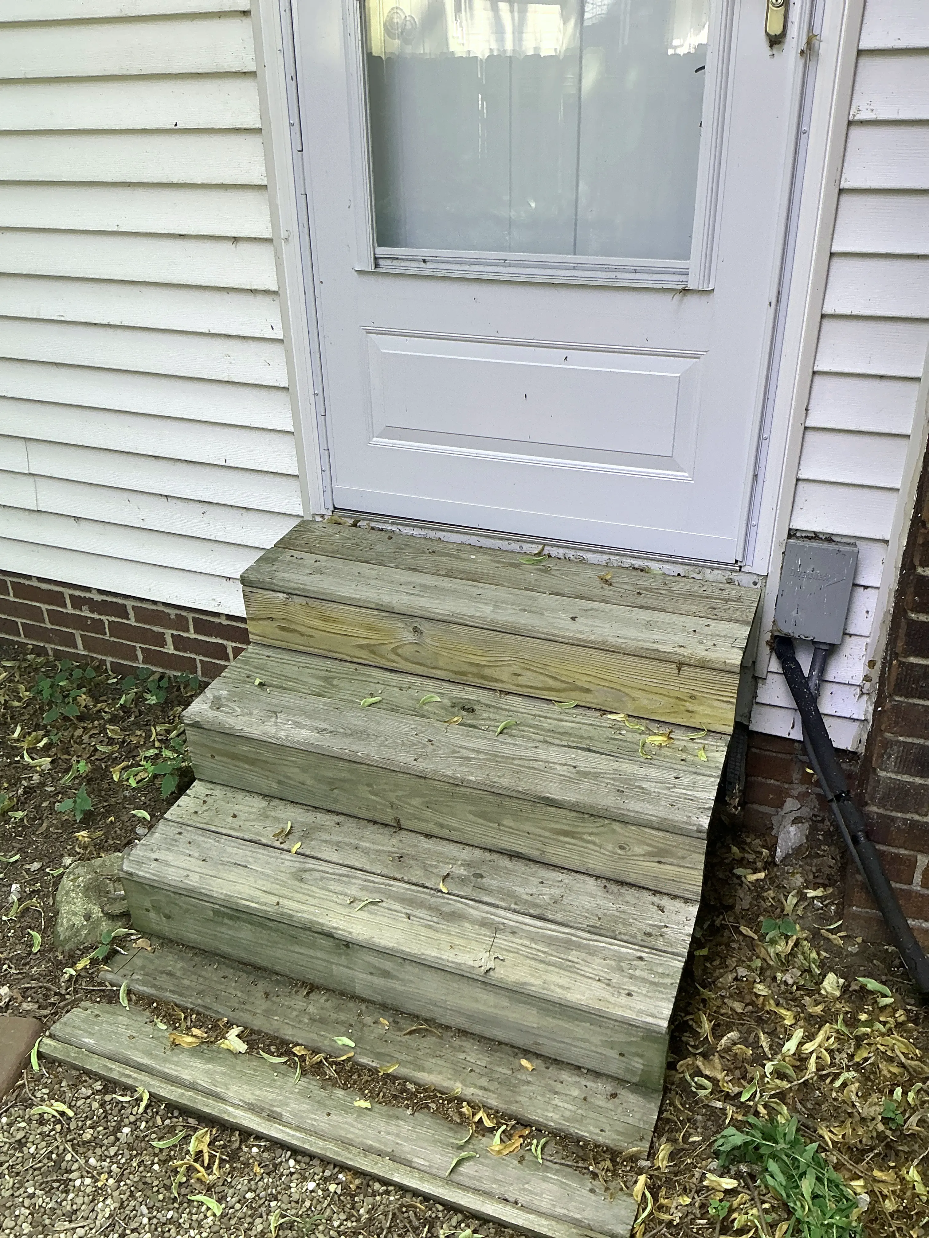 Weathered wooden stairs at an exterior entry door of a residence 2026-08-19