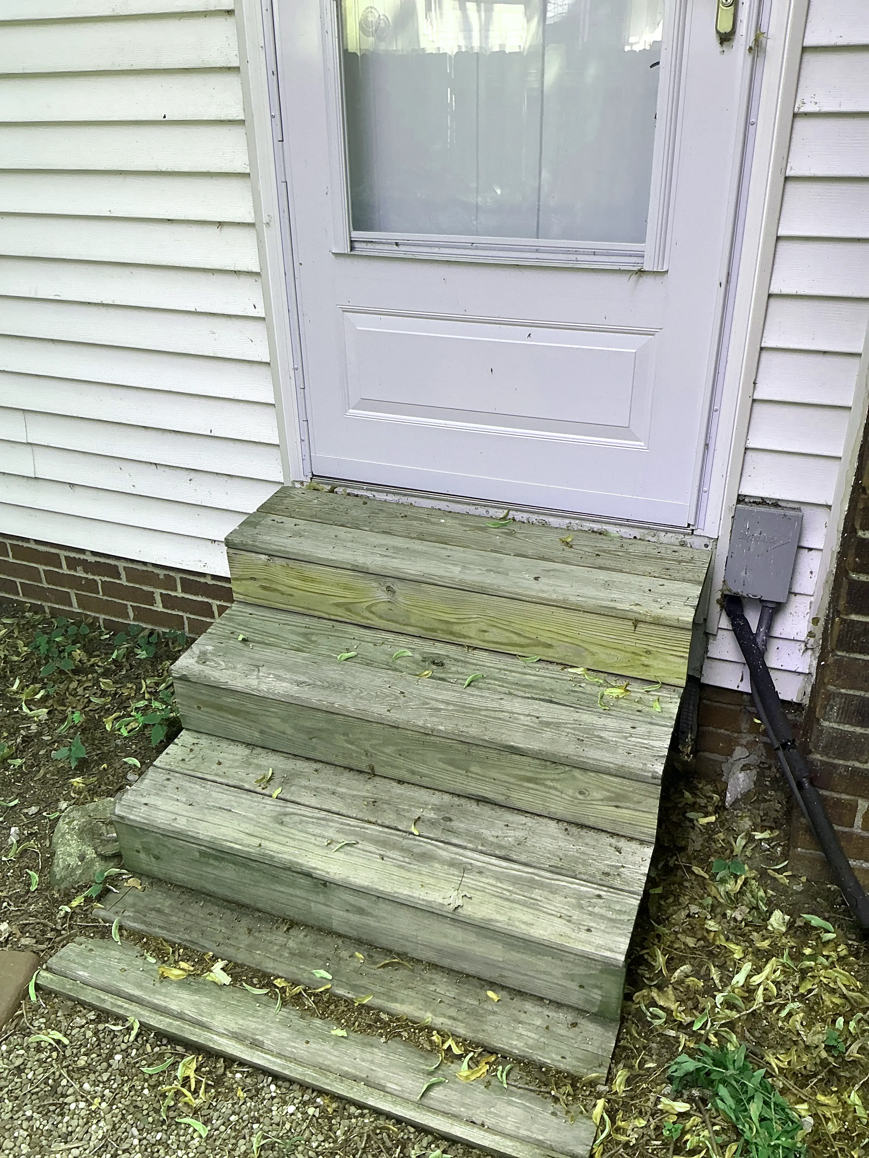 Weathered wooden stairs at an exterior entry door of a residence 2026-08-18