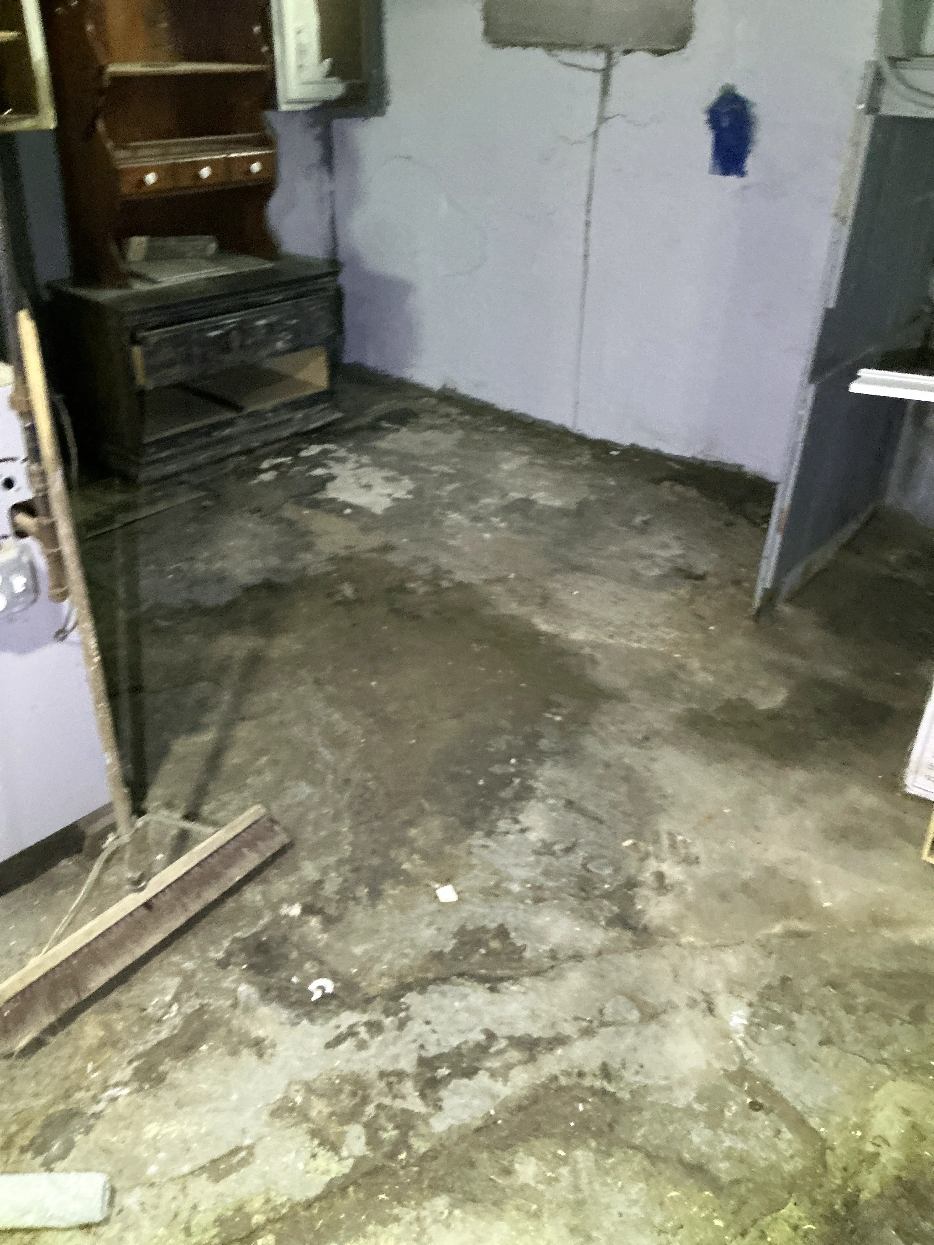 Unfinished concrete basement floor with dark water stains and moisture intrusion 2026-07-31