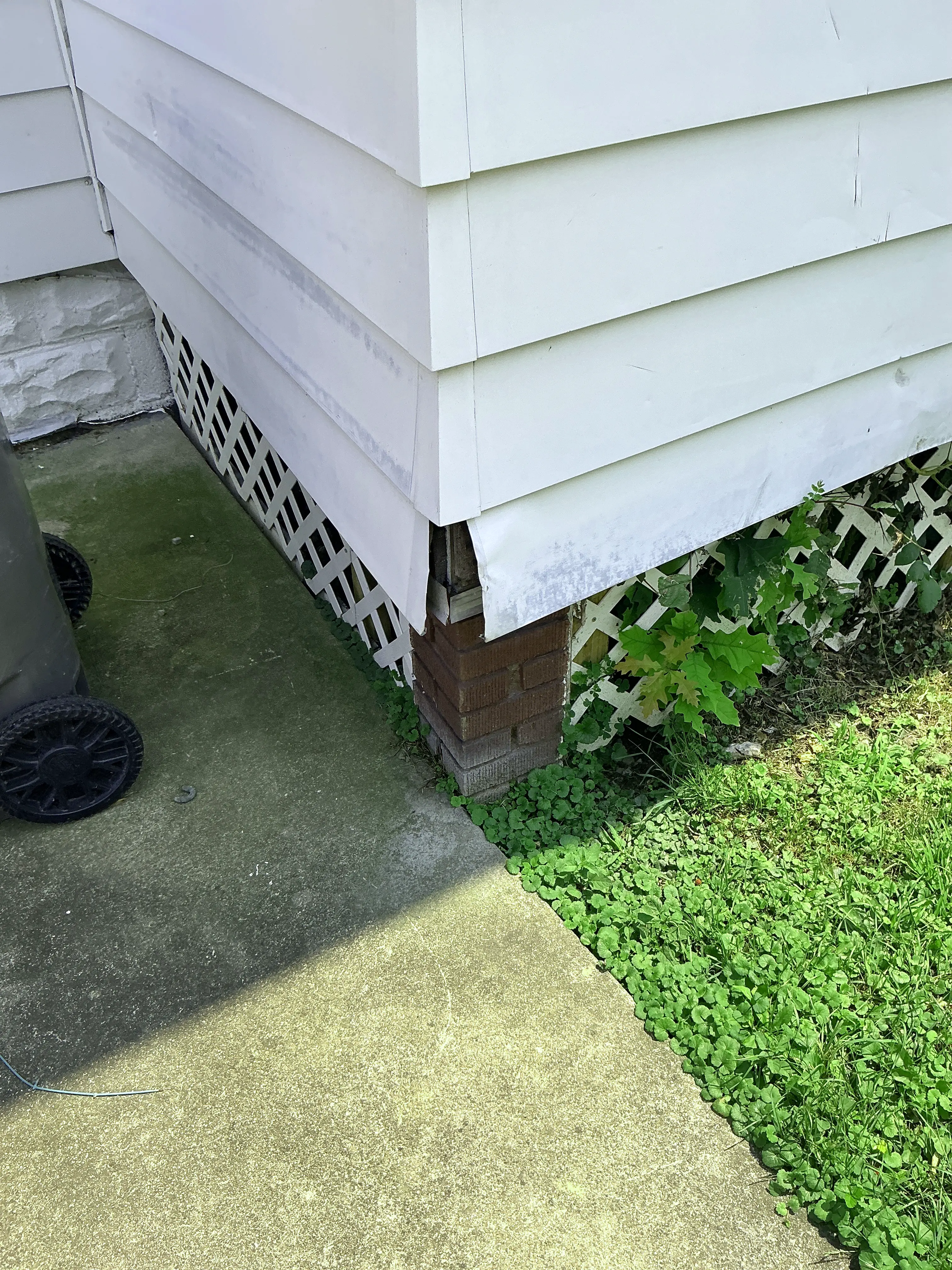 Damaged siding corner trim exposing exterior wood framing near foundation 2026-08-03