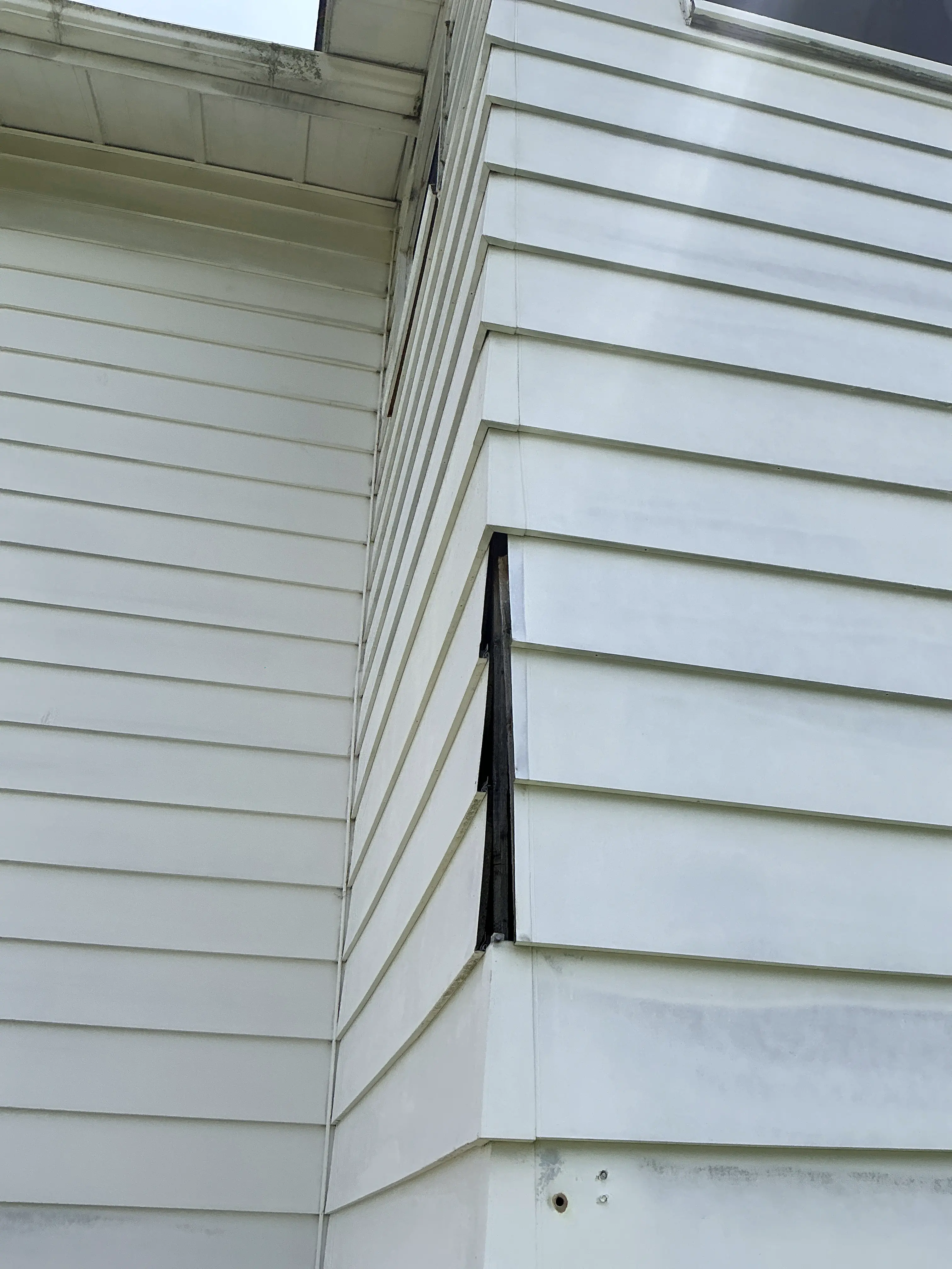 Separated white exterior siding panel exposing dark gap on residential home 2026-08-08