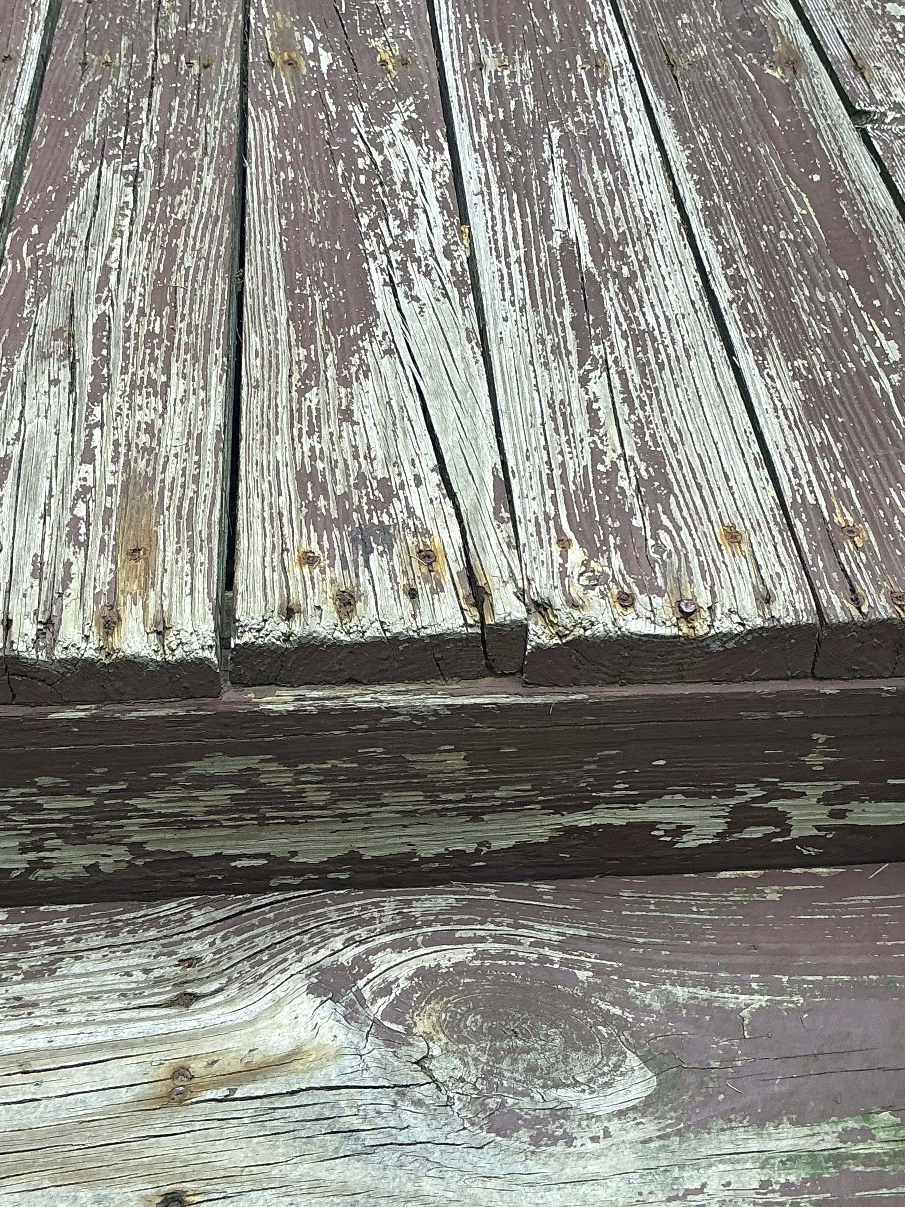 Peeling paint and exposed weathered wood grain on exterior house siding 2026-07-27