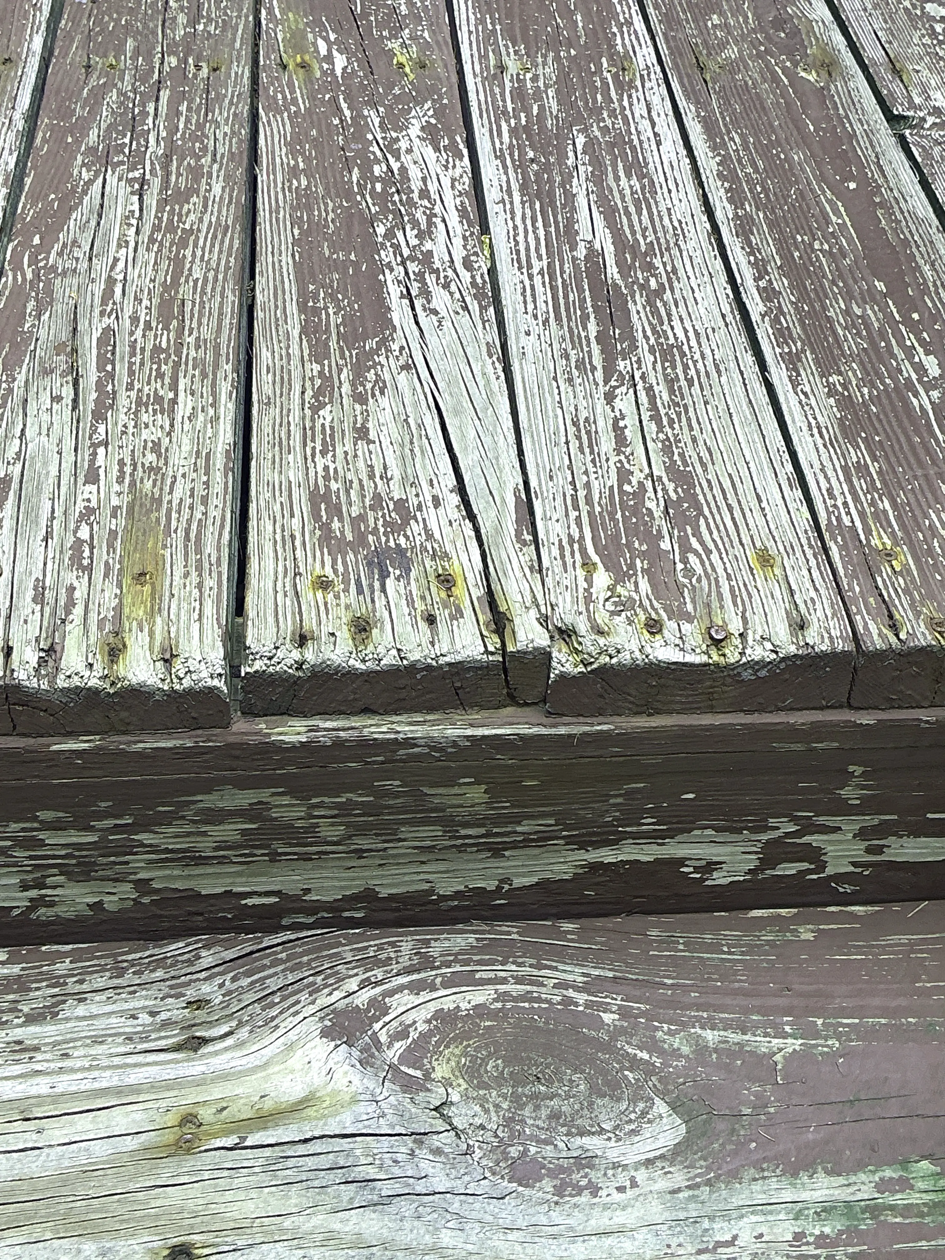 Peeling paint and exposed weathered wood grain on exterior house siding 2026-08-11