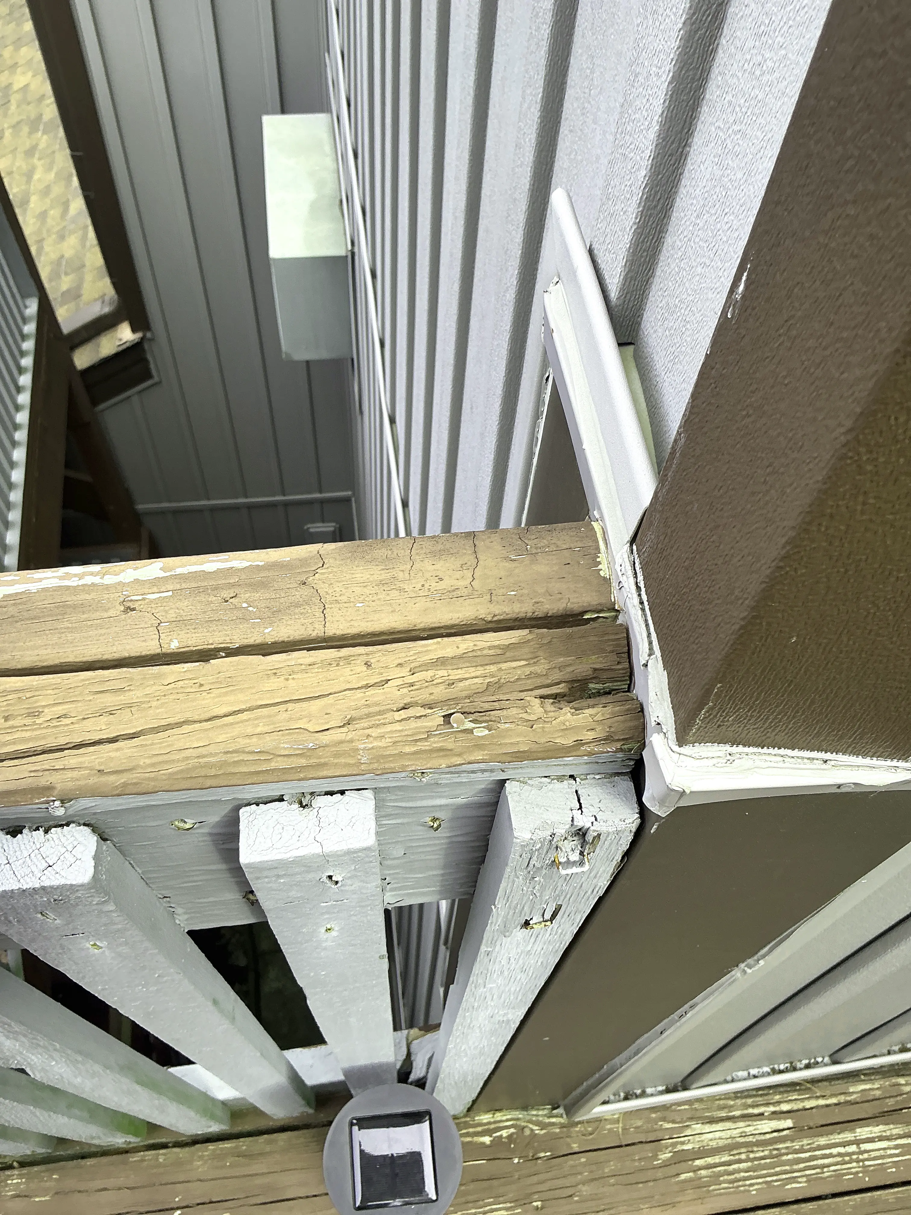 Extensive paint peeling and weathered wood decay on an exterior porch post and trim 2026-07-23