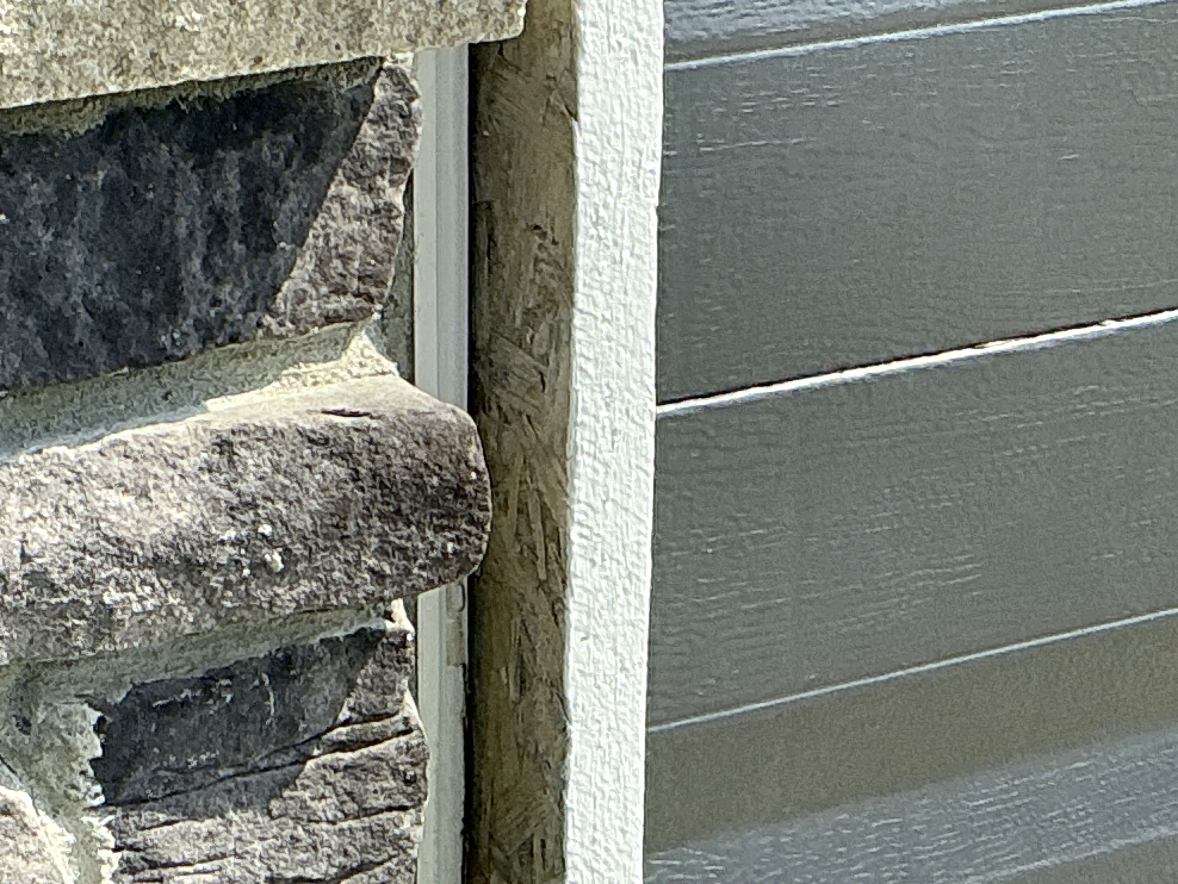 Exposed OSB sheathing and unsealed gap between stone veneer siding and exterior wall trim 2026-08-28