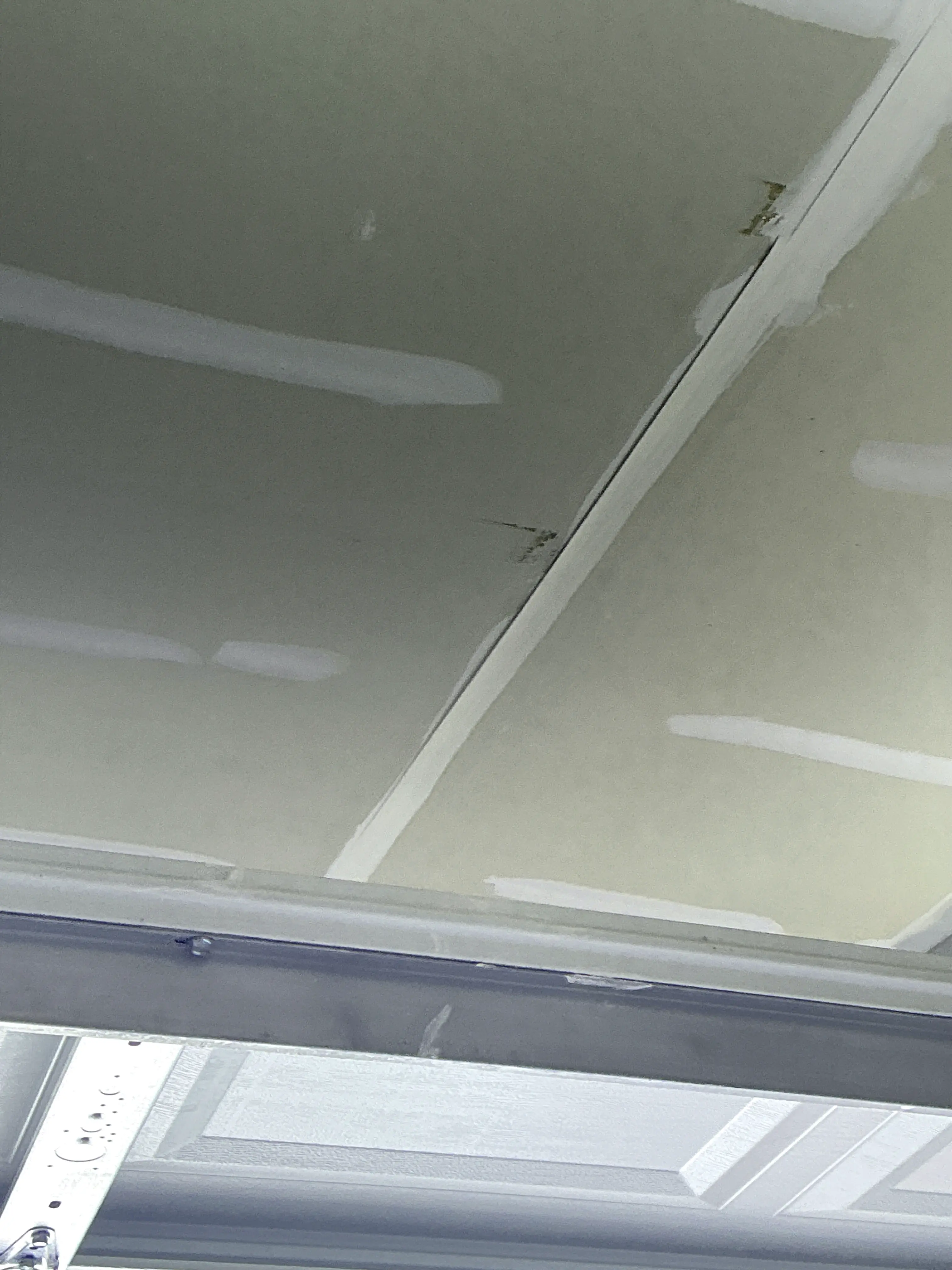 Unfinished drywall joint tape near the garage ceiling corner seam 2026-08-12
