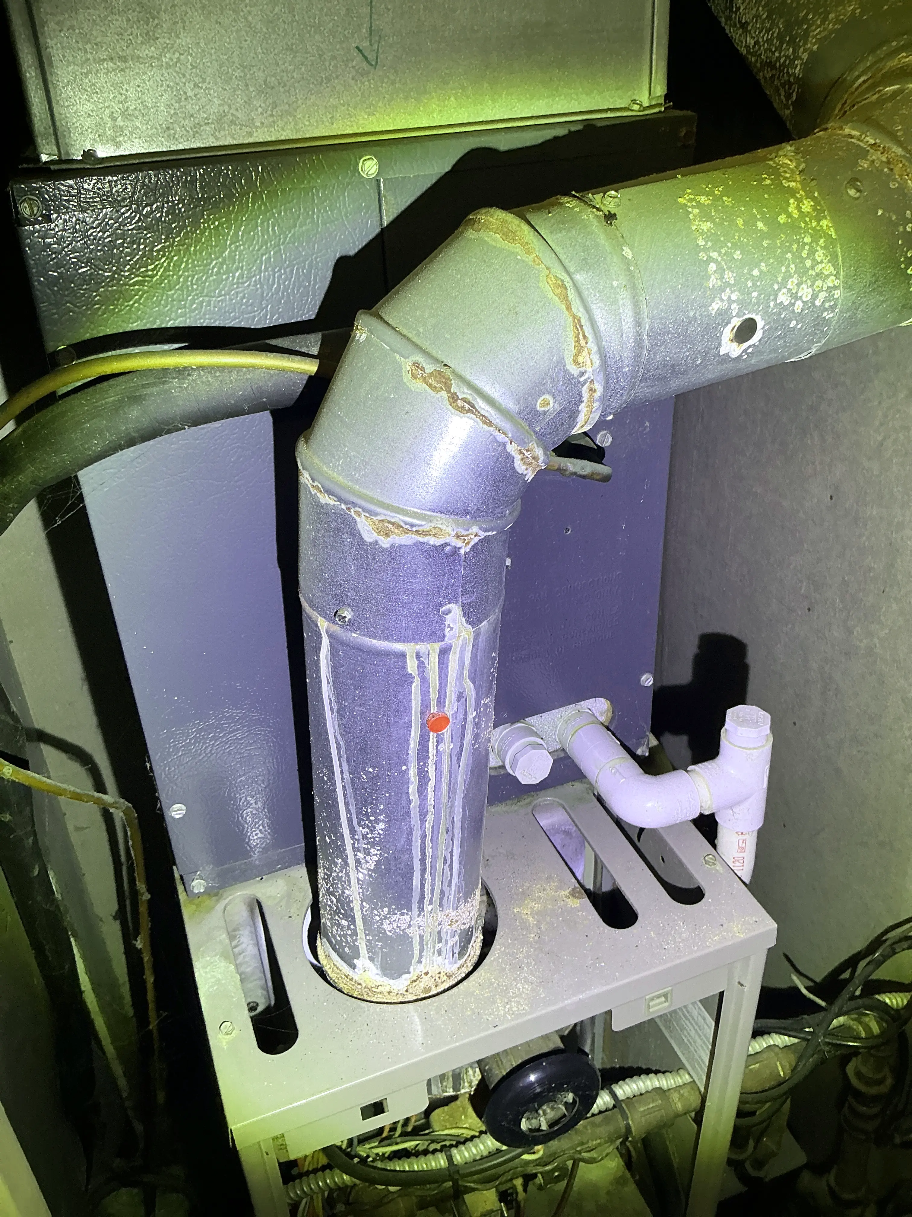 Rust and corrosion visible on a metal furnace flue pipe during a indoor air quality testing 2026-08-08