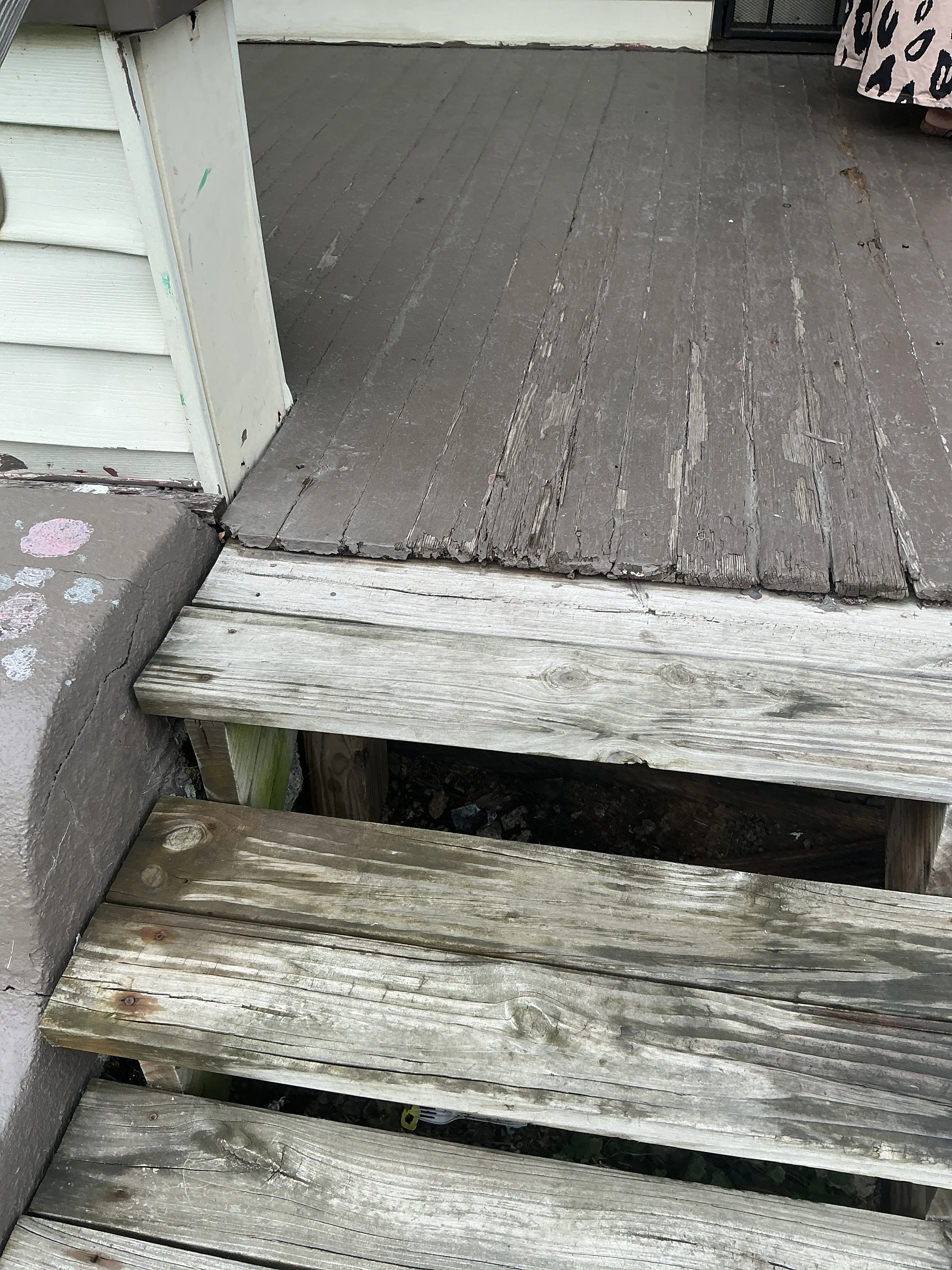 Deteriorated wooden porch flooring and step boards in need of repair. 2026-07-30