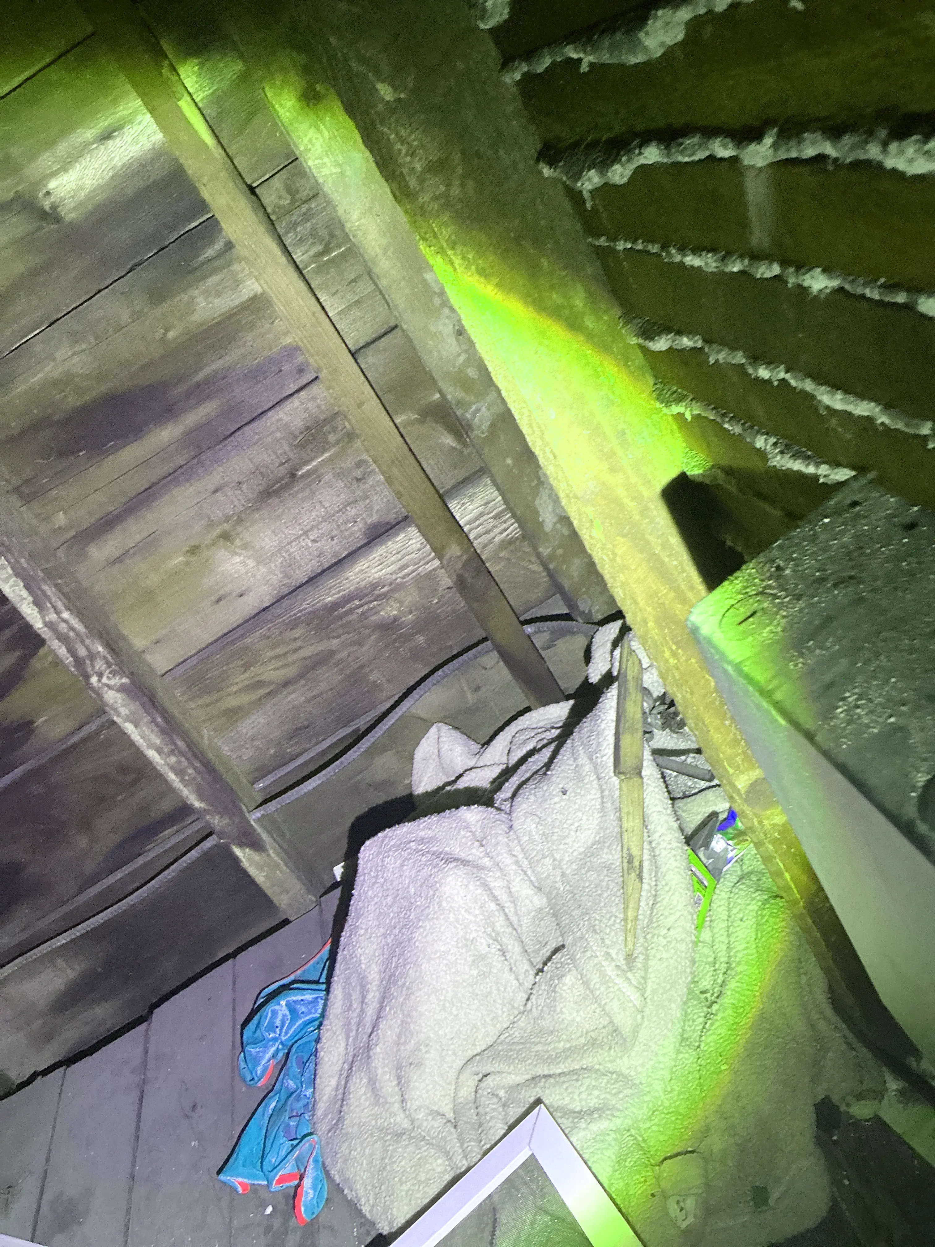Attic inspection showing wooden rafters, floorboards, and stored personal clutter. 2026-07-24