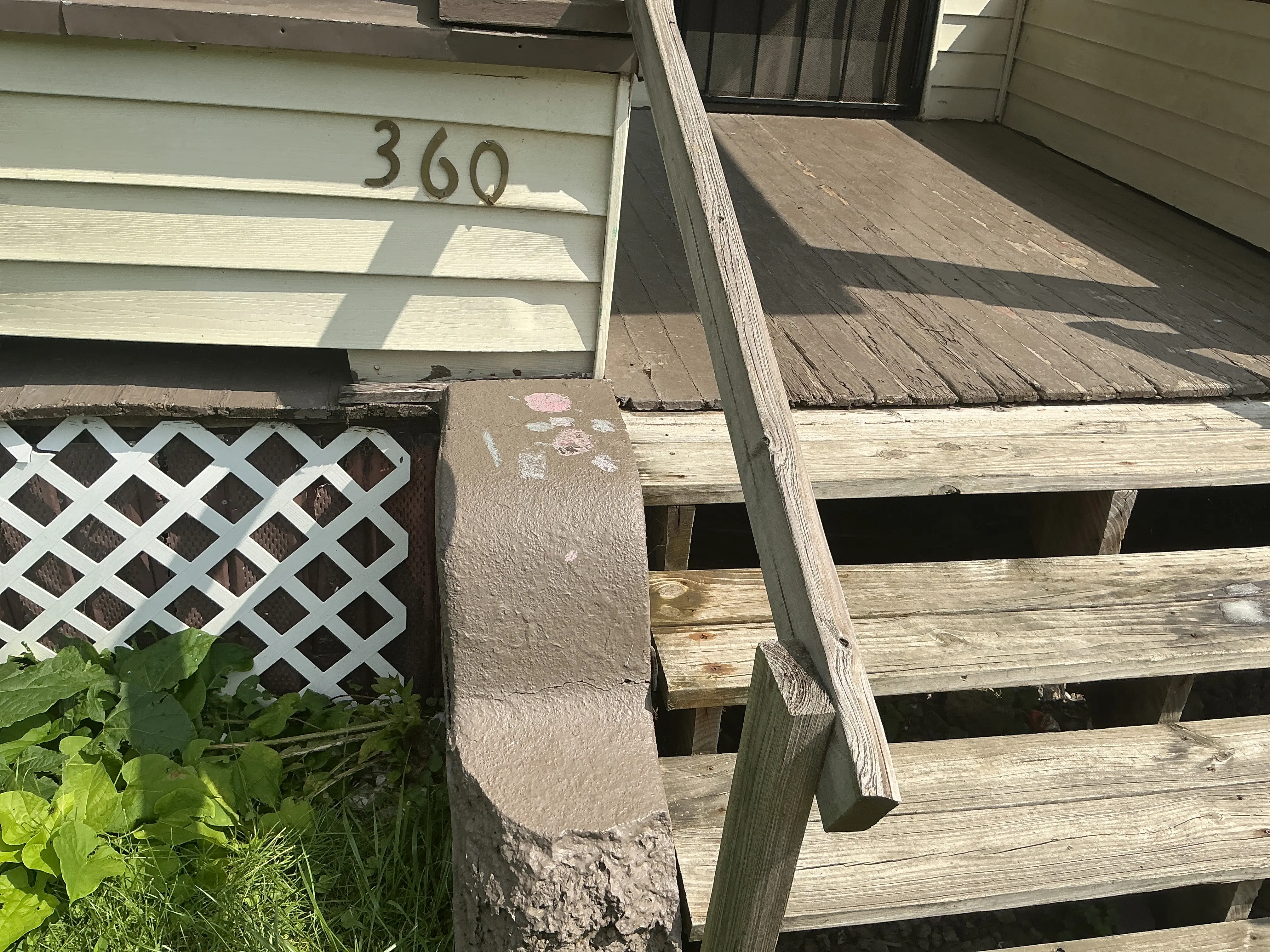 Weathered wooden porch steps and handrail on house exterior 2026-07-20