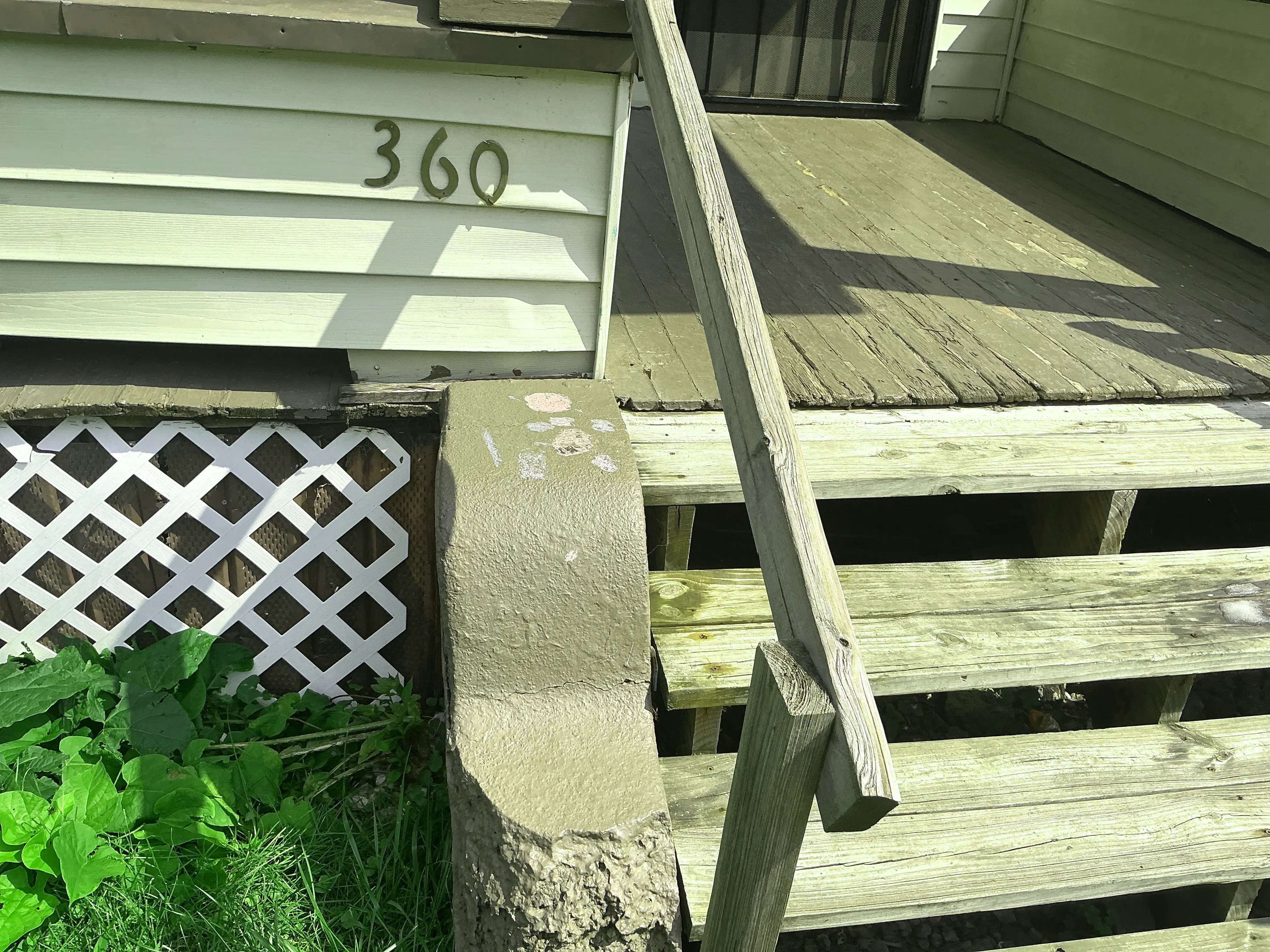 Weathered wooden porch steps and handrail on house exterior 2026-08-27
