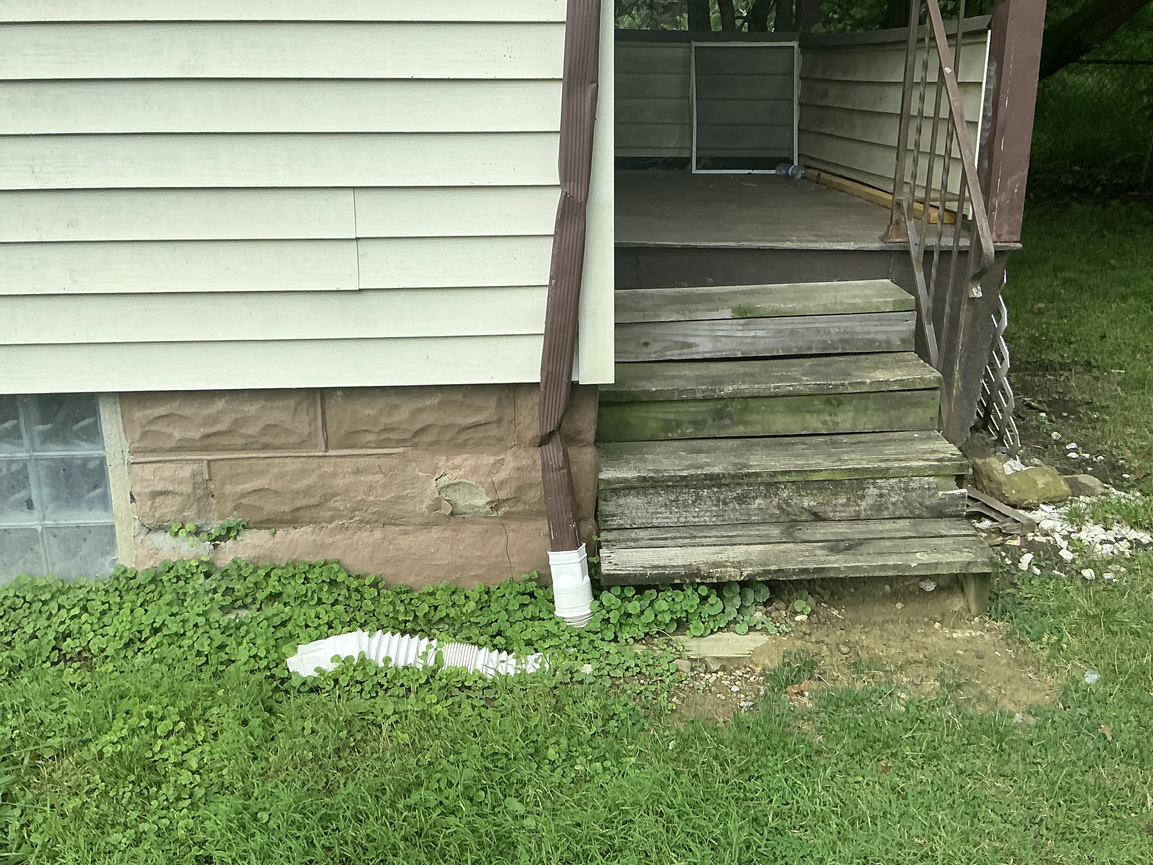 Damaged downspout and flexible extension near foundation wall of a house 2026-08-27