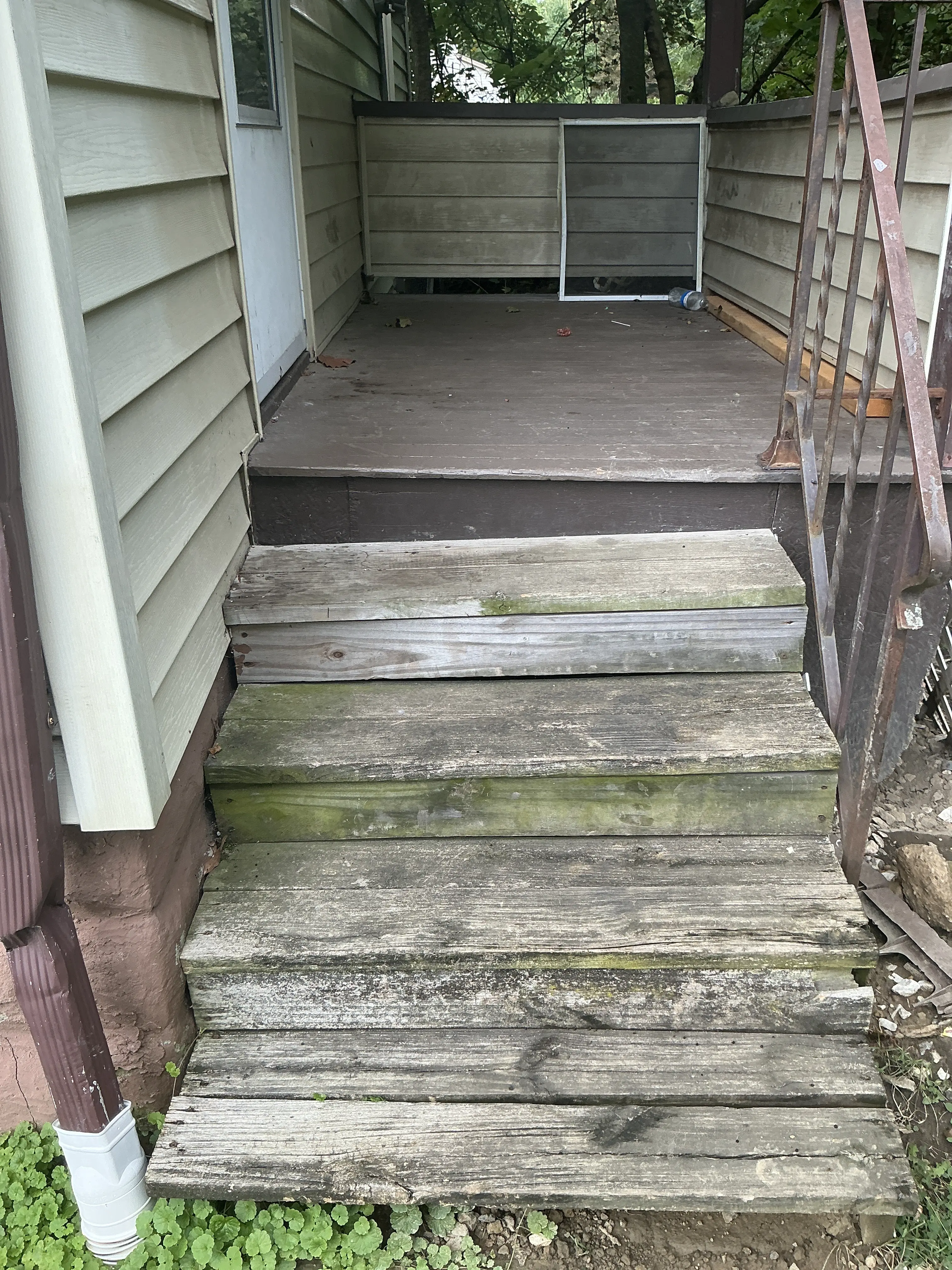 Weathered wooden exterior stairs with moss growth and rusted railing 2026-08-17
