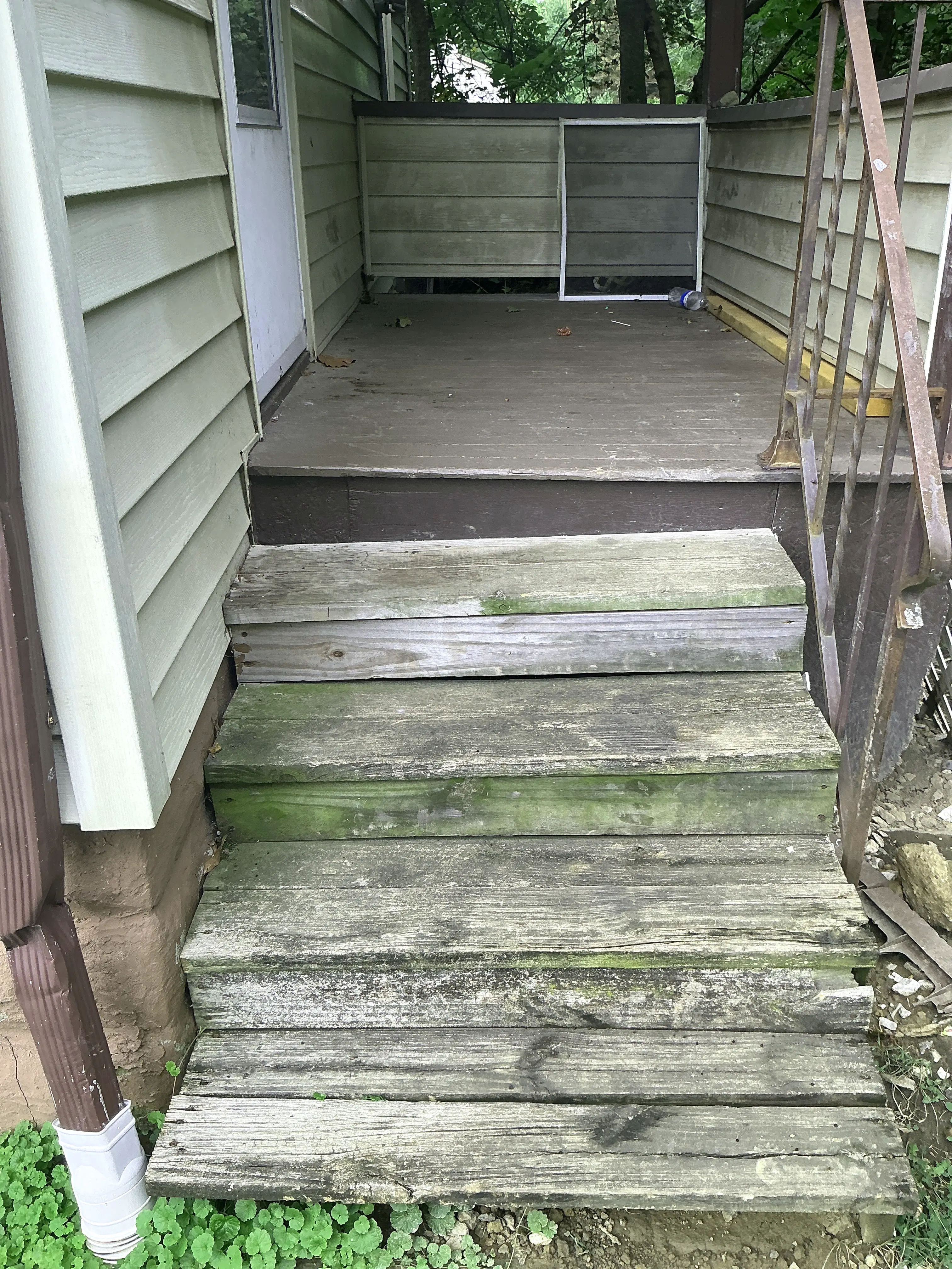 Weathered wooden exterior stairs with moss growth and rusted railing 2026-07-22