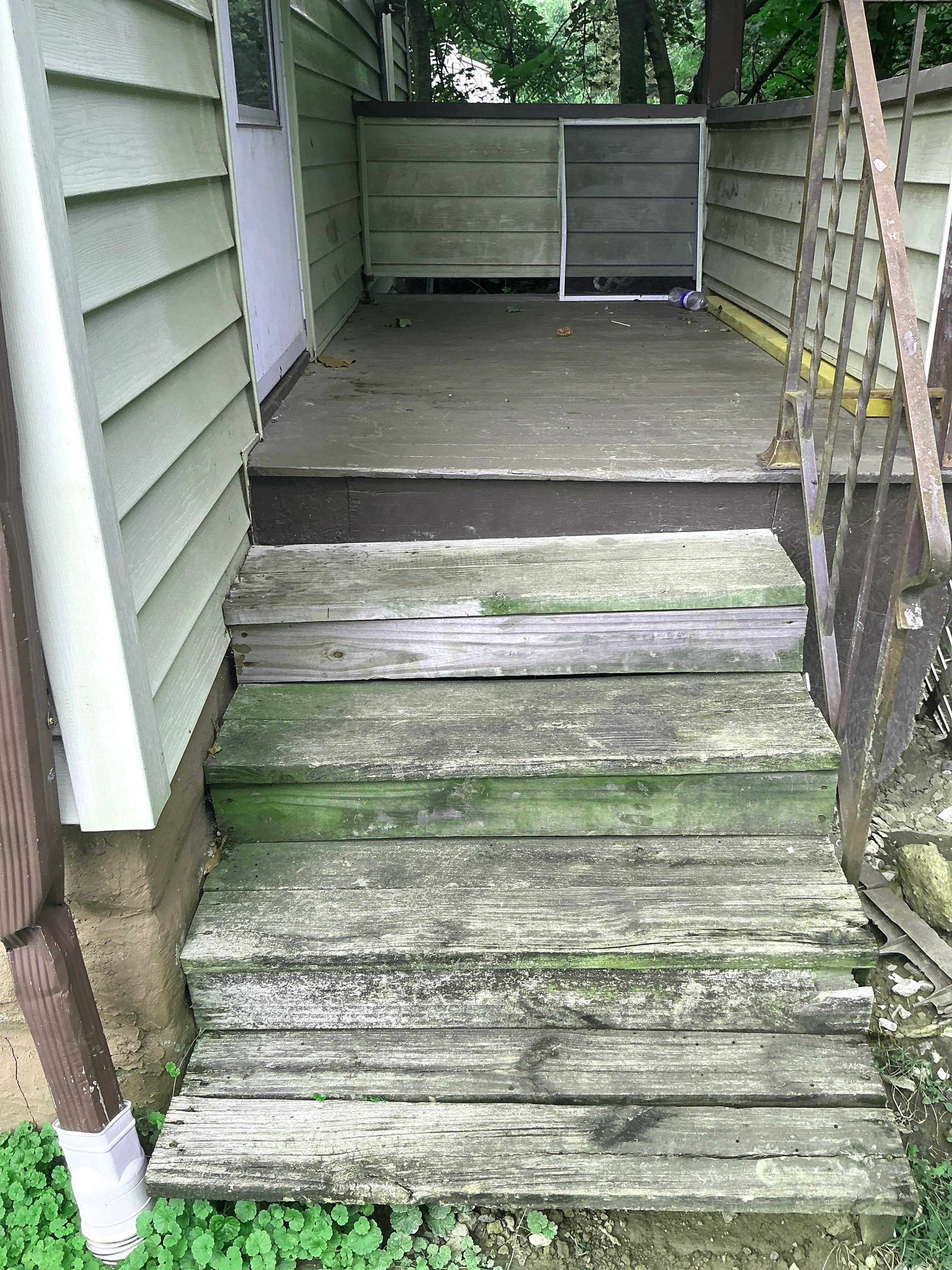 Weathered wooden exterior stairs with moss growth and rusted railing 2026-07-09