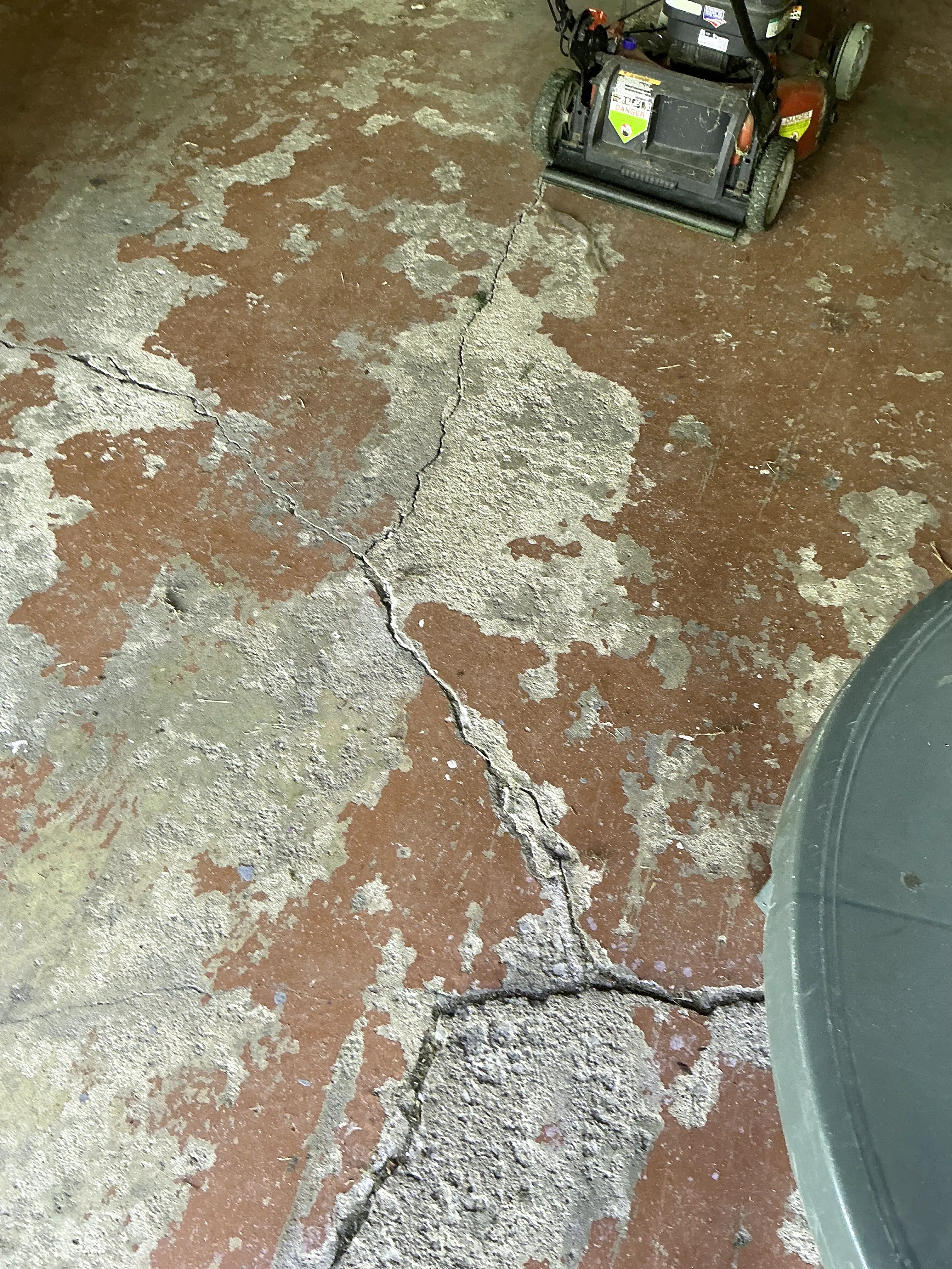 Cracked concrete garage floor with peeling red paint 2026-08-10