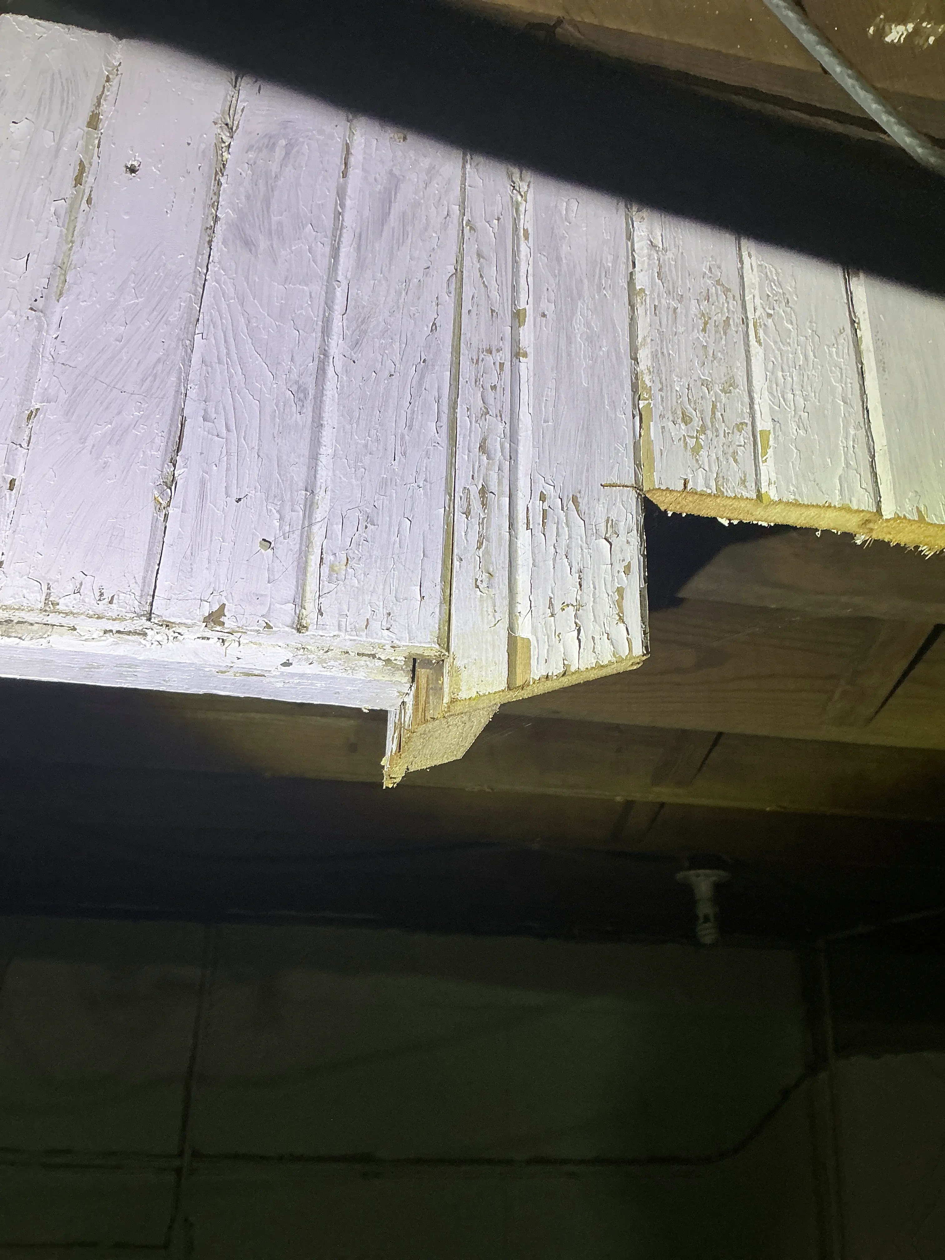 Old painted wood siding cut open inside an attic with peeling paint 2026-08-18