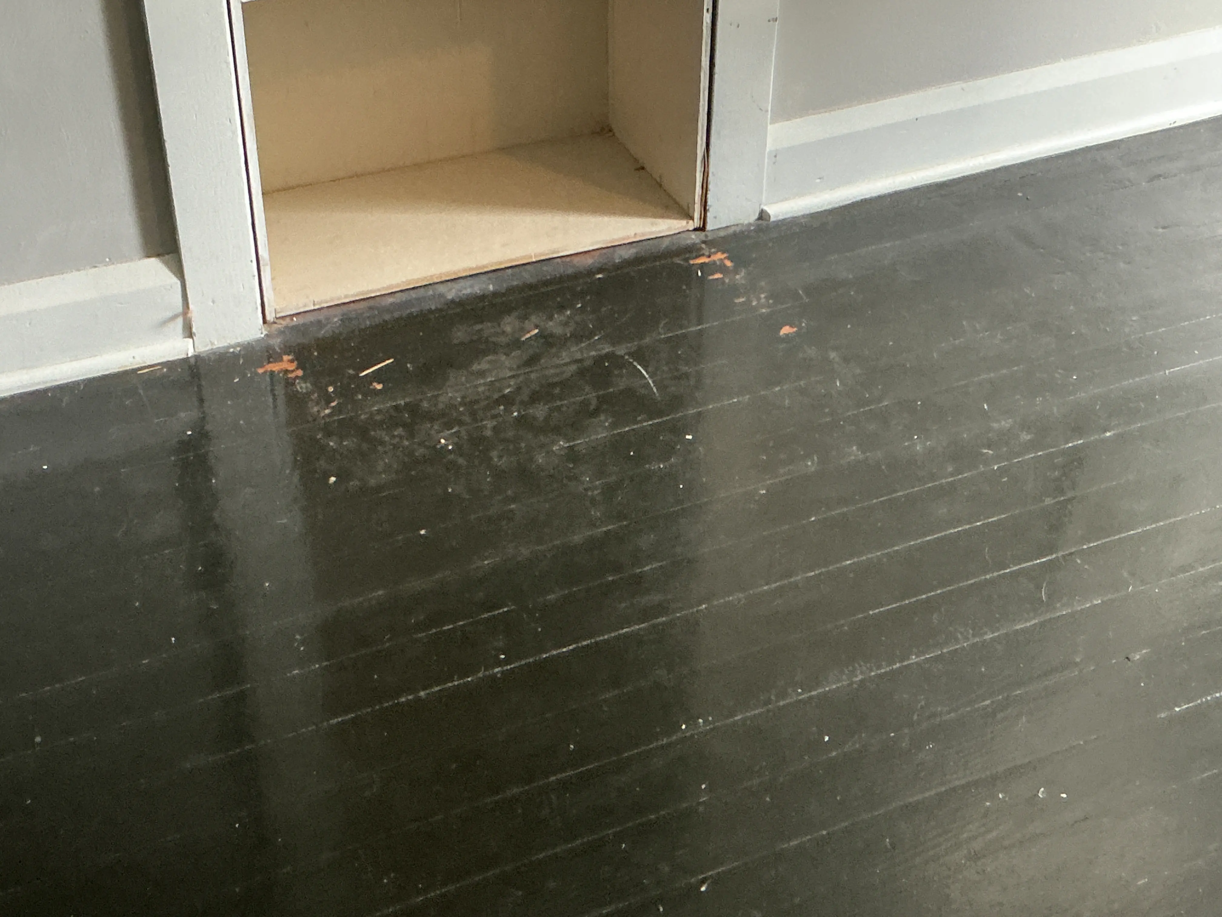 Chipped paint and surface wear on dark hardwood flooring 2026-07-05
