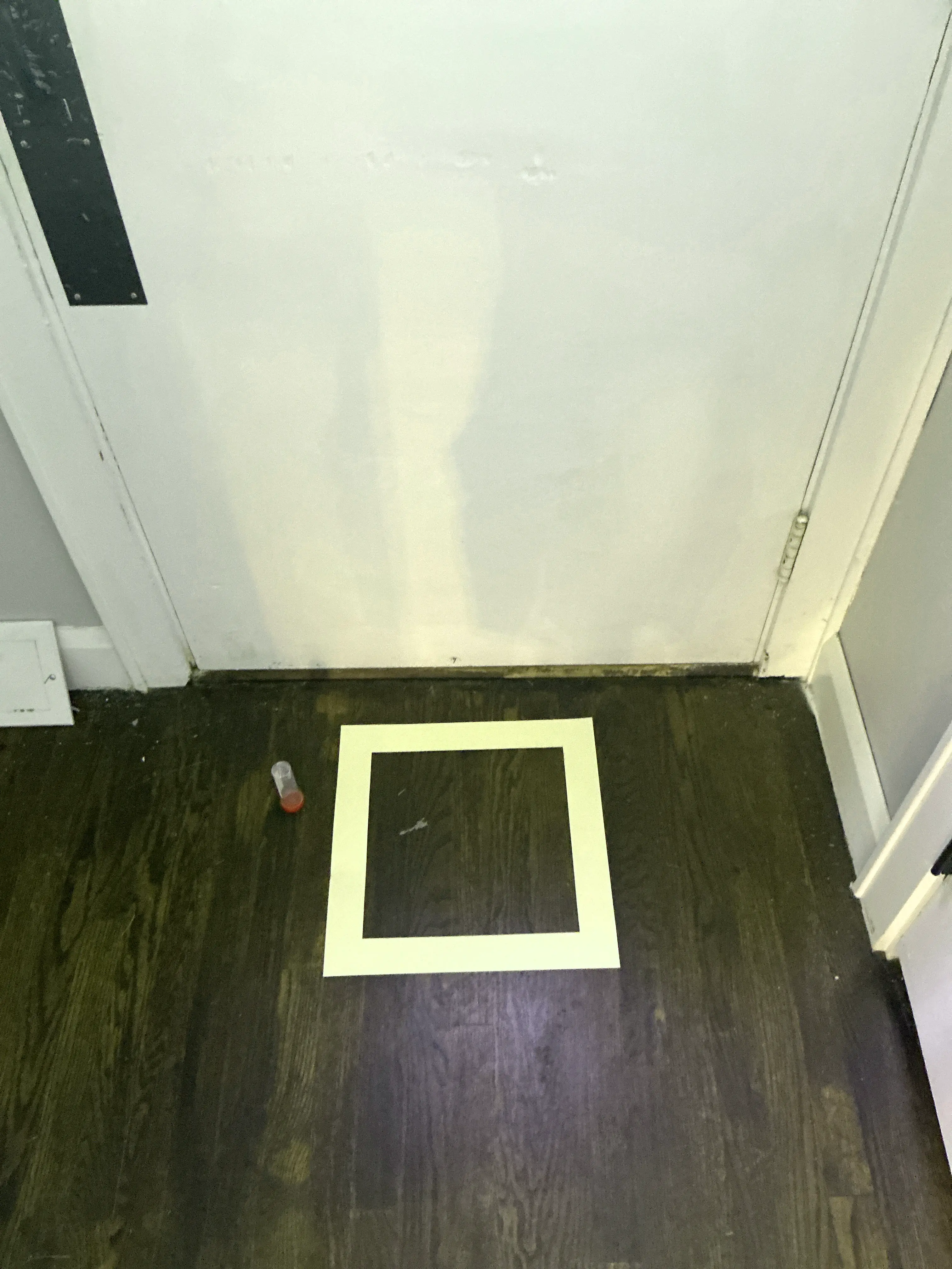 Taped surface test area on dark wood paneling with a sample collection vial during a home inspection 2026-07-16