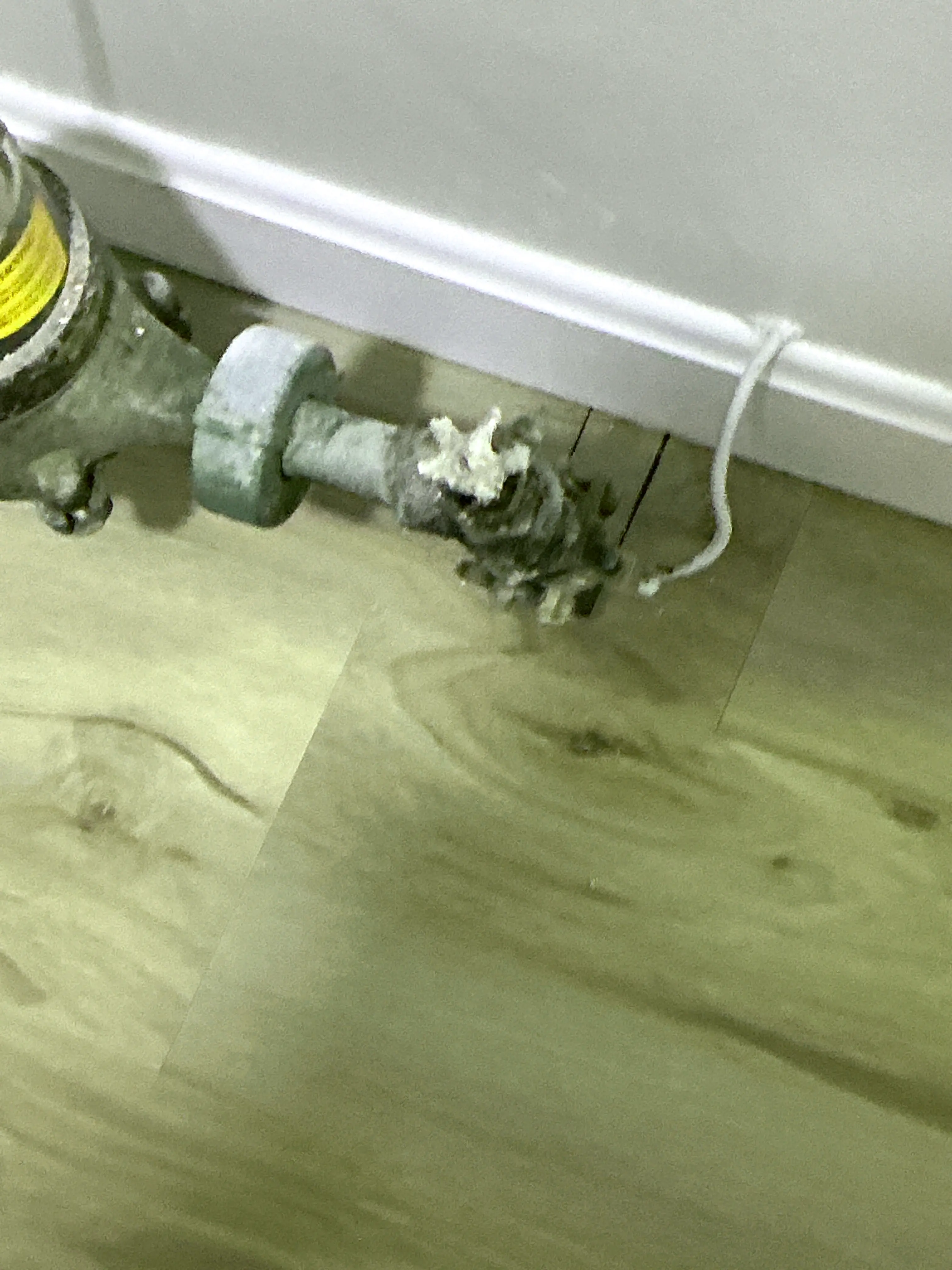 Corroded radiator valve near baseboard showing severe mineral buildup from leaking 2026-08-31