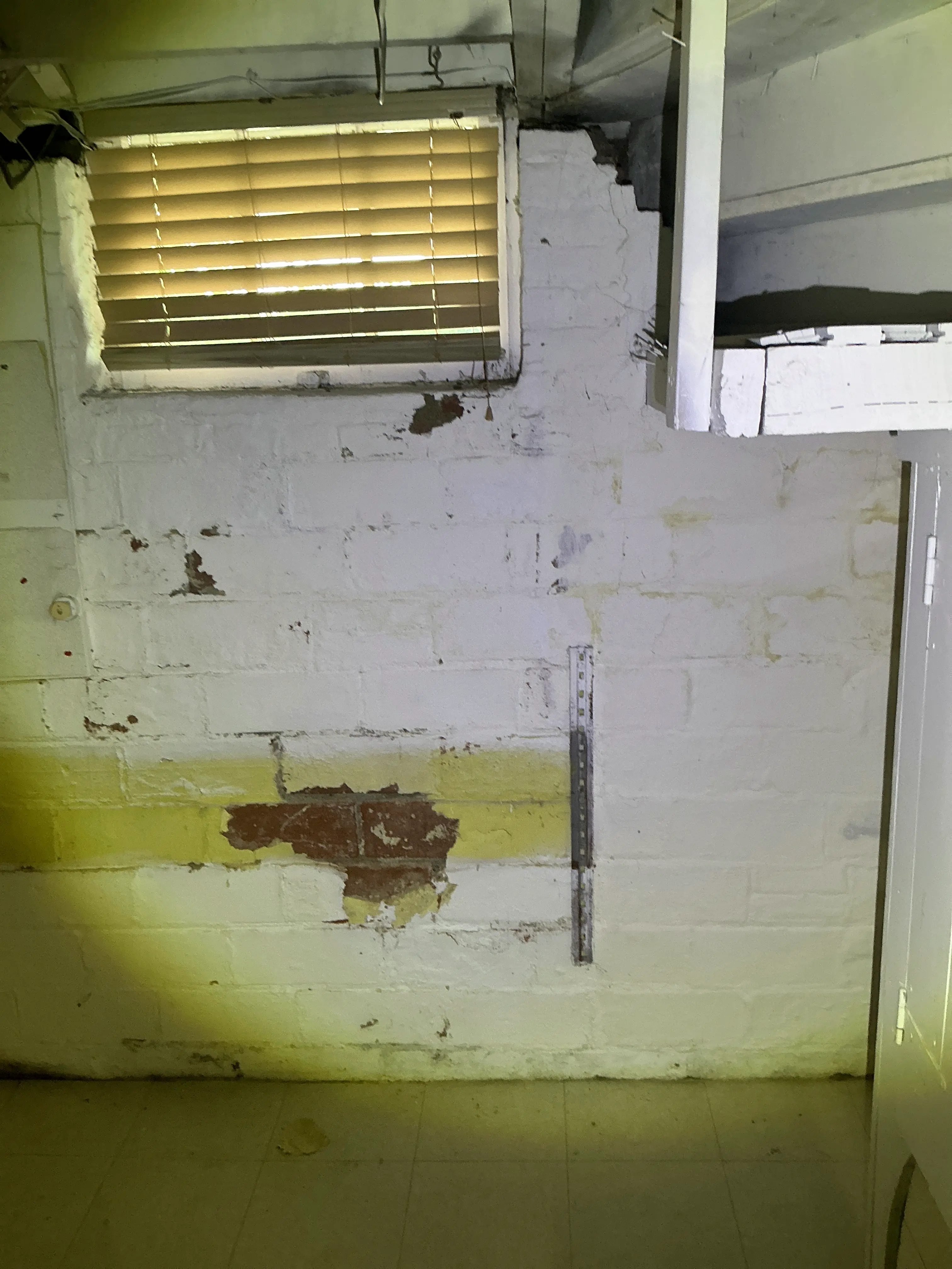 Peeling paint and exposed brick masonry on an interior wall during indoor air quality testing 2026-08-25