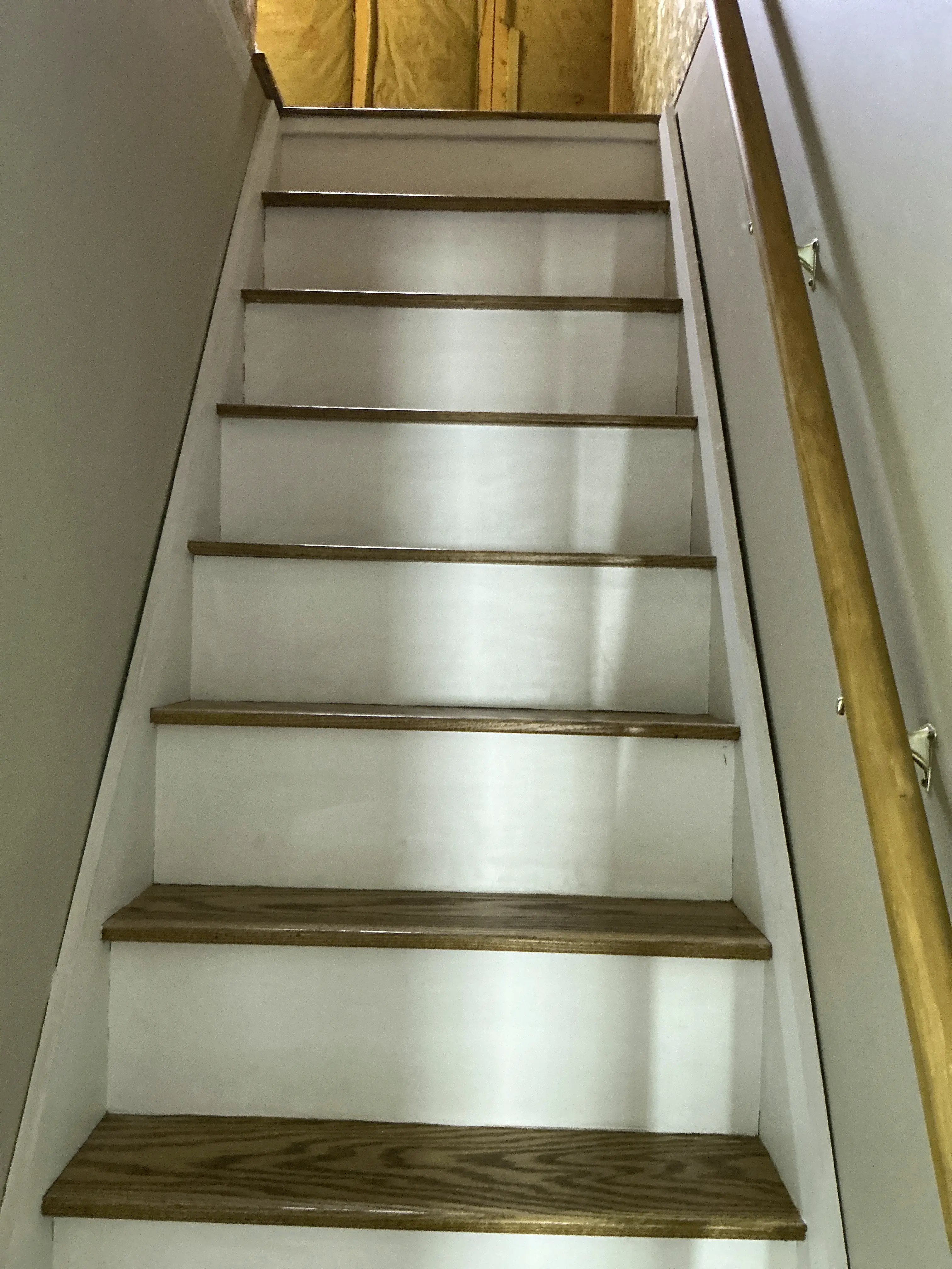 View looking down a residential interior staircase with wooden handrail and white treads 2026-08-17