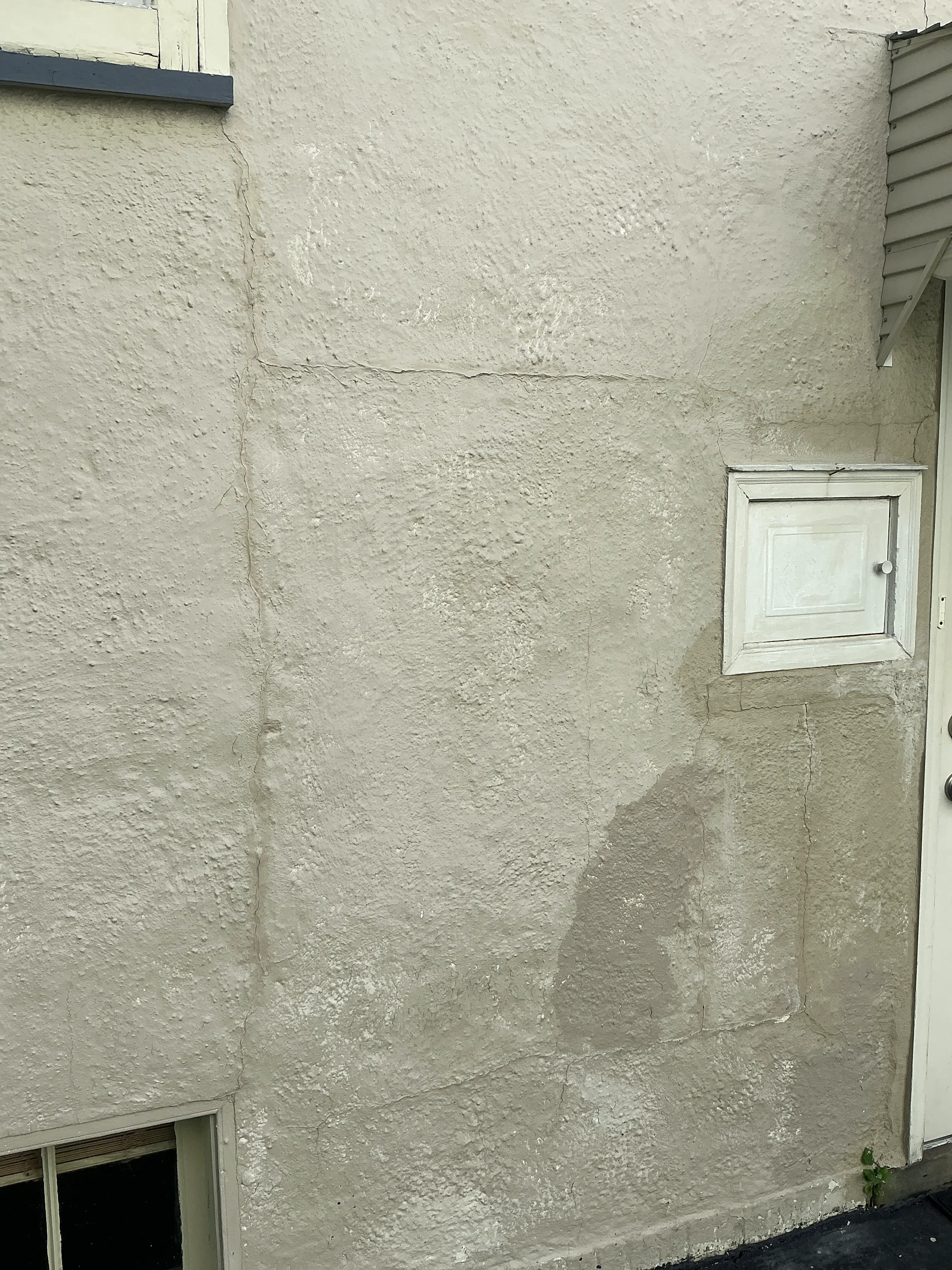 Cracks and patched stucco exterior wall observed during indoor air quality testing 2026-08-14