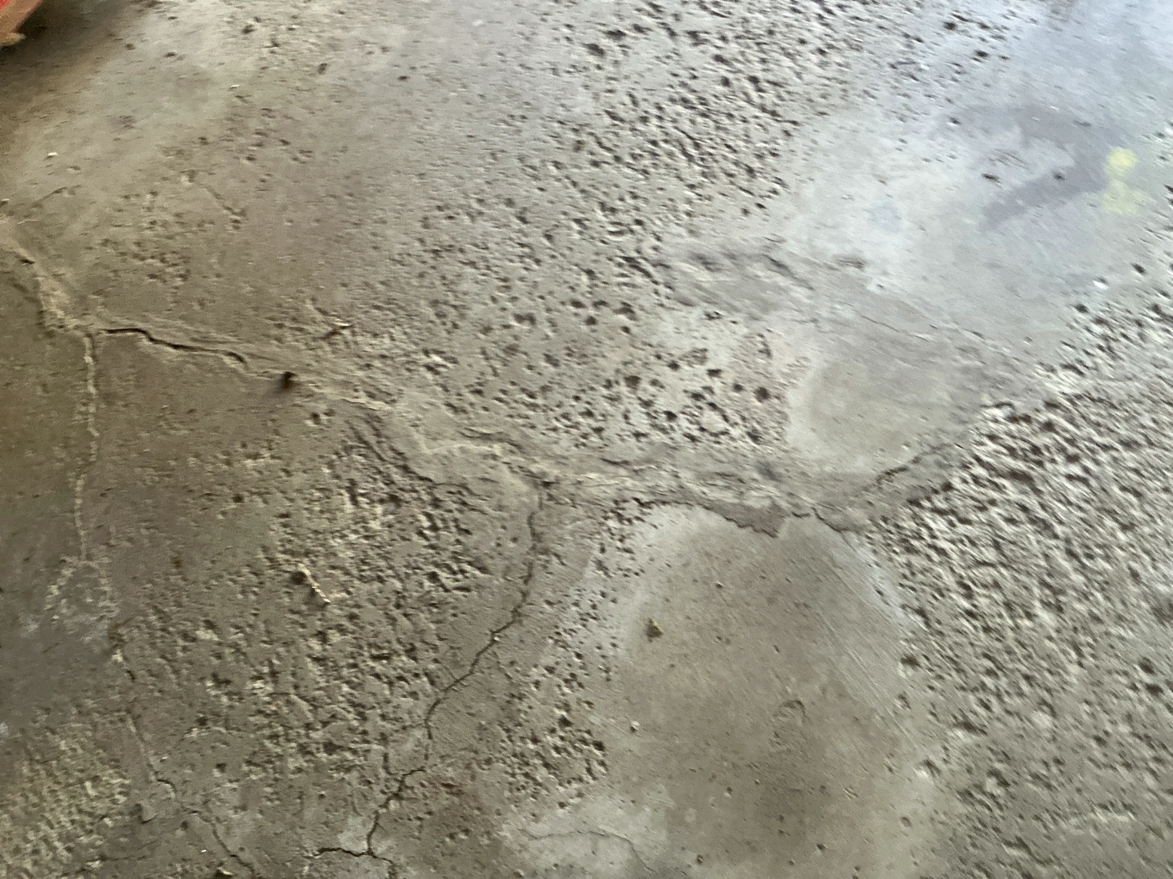 Cracked and pitted concrete floor slab showing surface deterioration during home inspection 2026-07-27